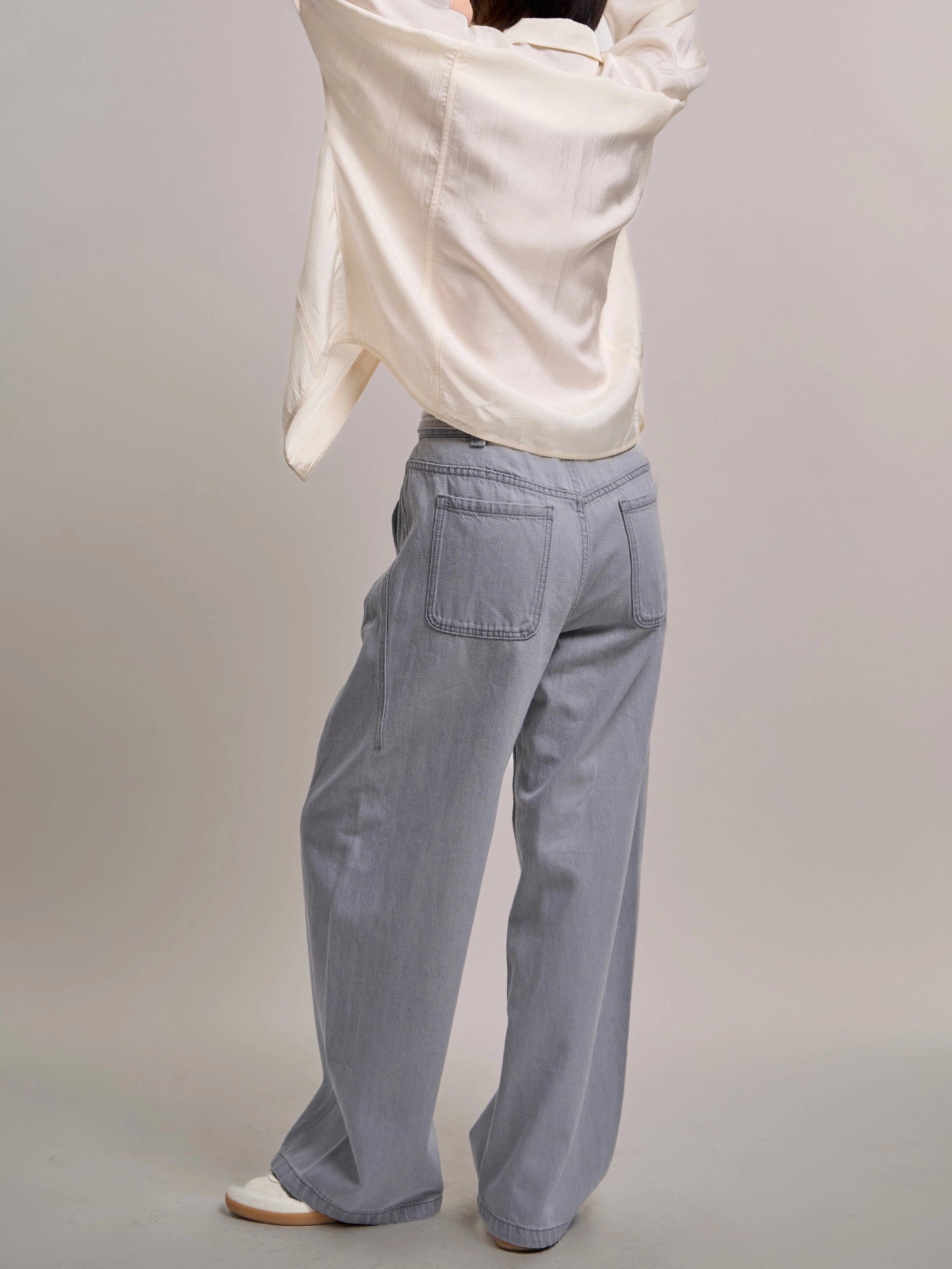 Side-back angle of Curved Cocoon Jeans highlighting curved outer seams and natural denim drape.