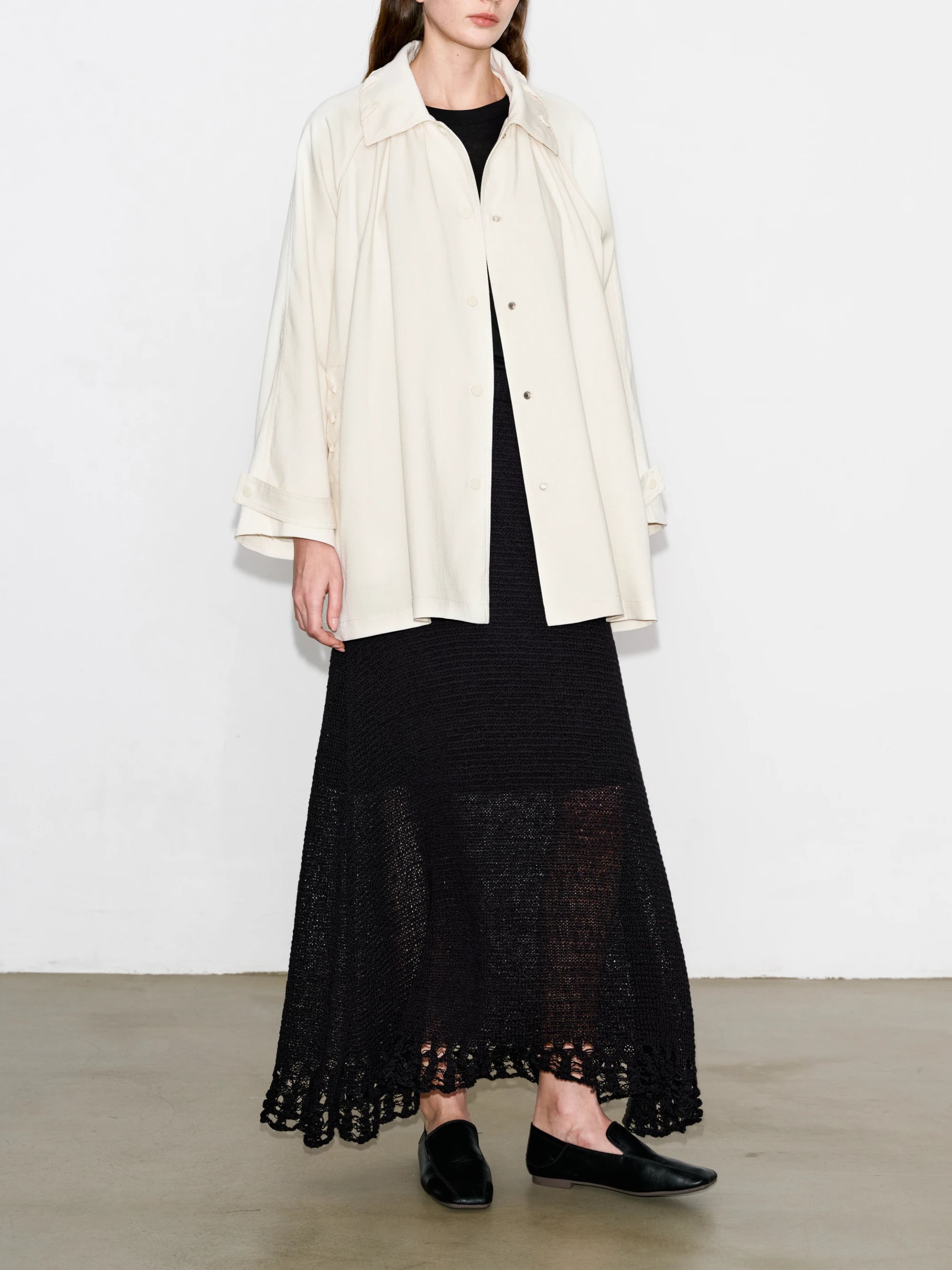 Ivory Drift Overshirt front view, wide sleeves and drawstring neckline, styled with long black skirt.