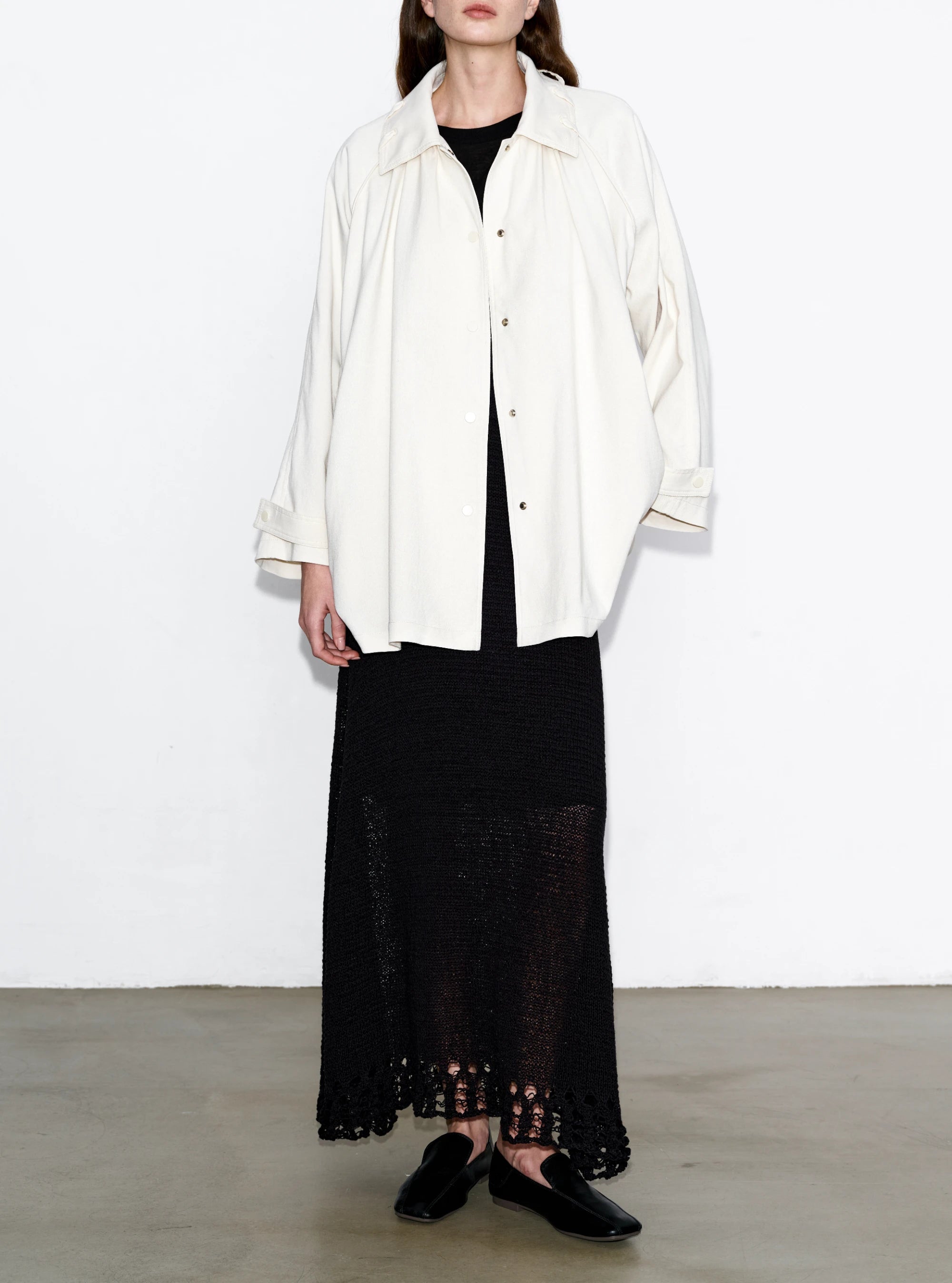 Model wearing ivory Drift Overshirt, relaxed dropped-shoulder fit paired with black skirt, full front styling view.