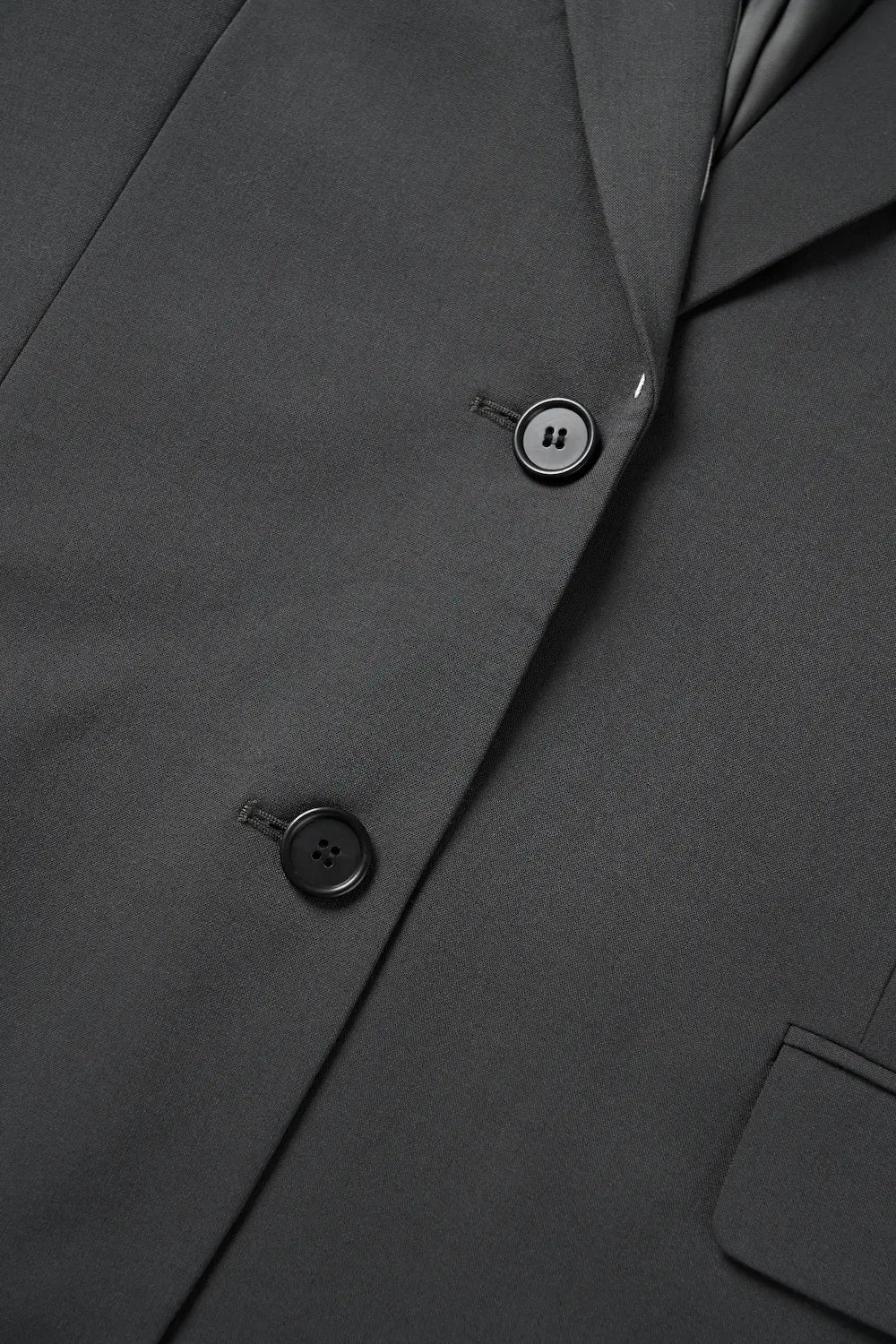 Close-up of the front button fastening and texture of the XXL Smile charcoal blazer.