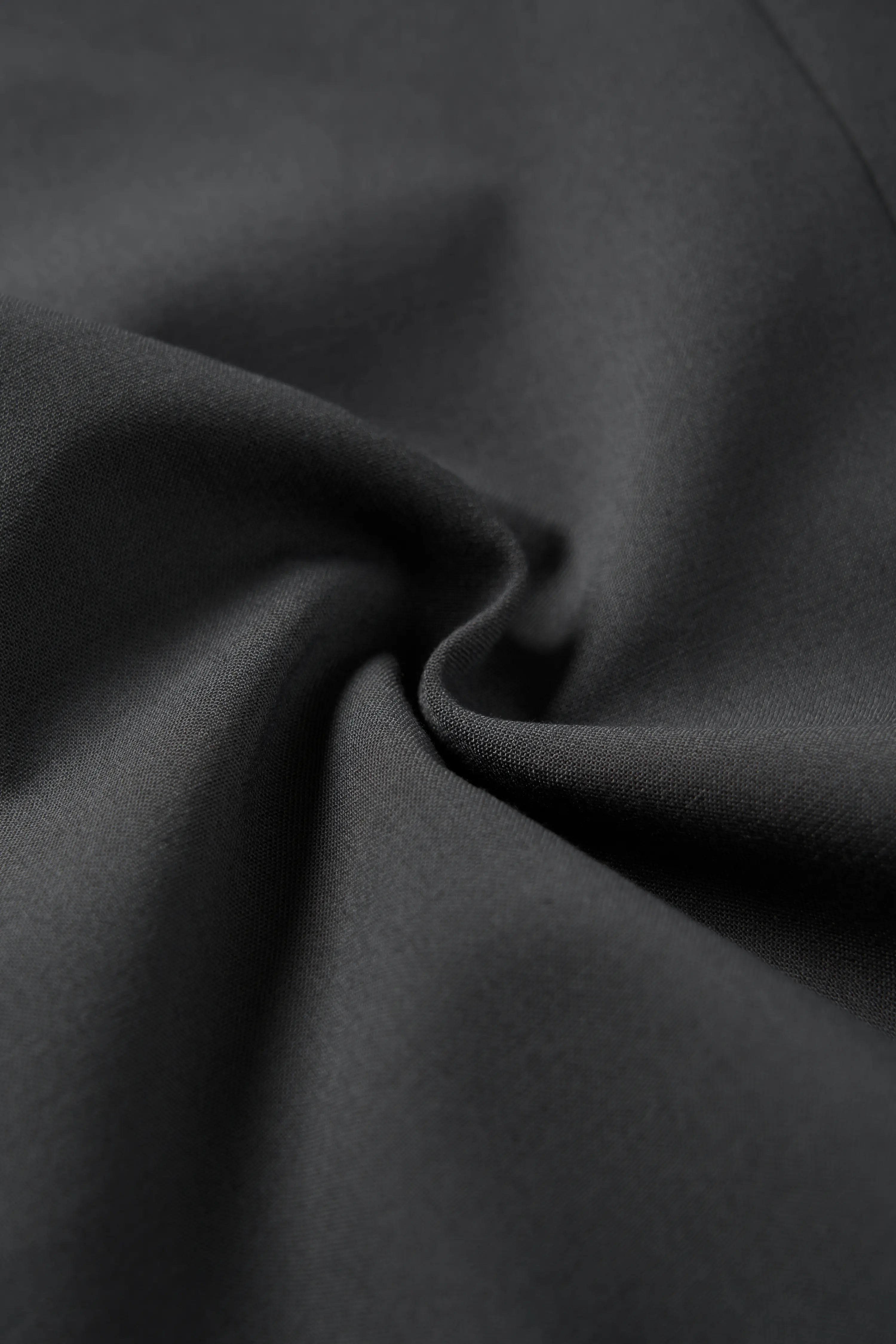 Macro shot showing the high-quality charcoal fabric texture and material of the blazer.