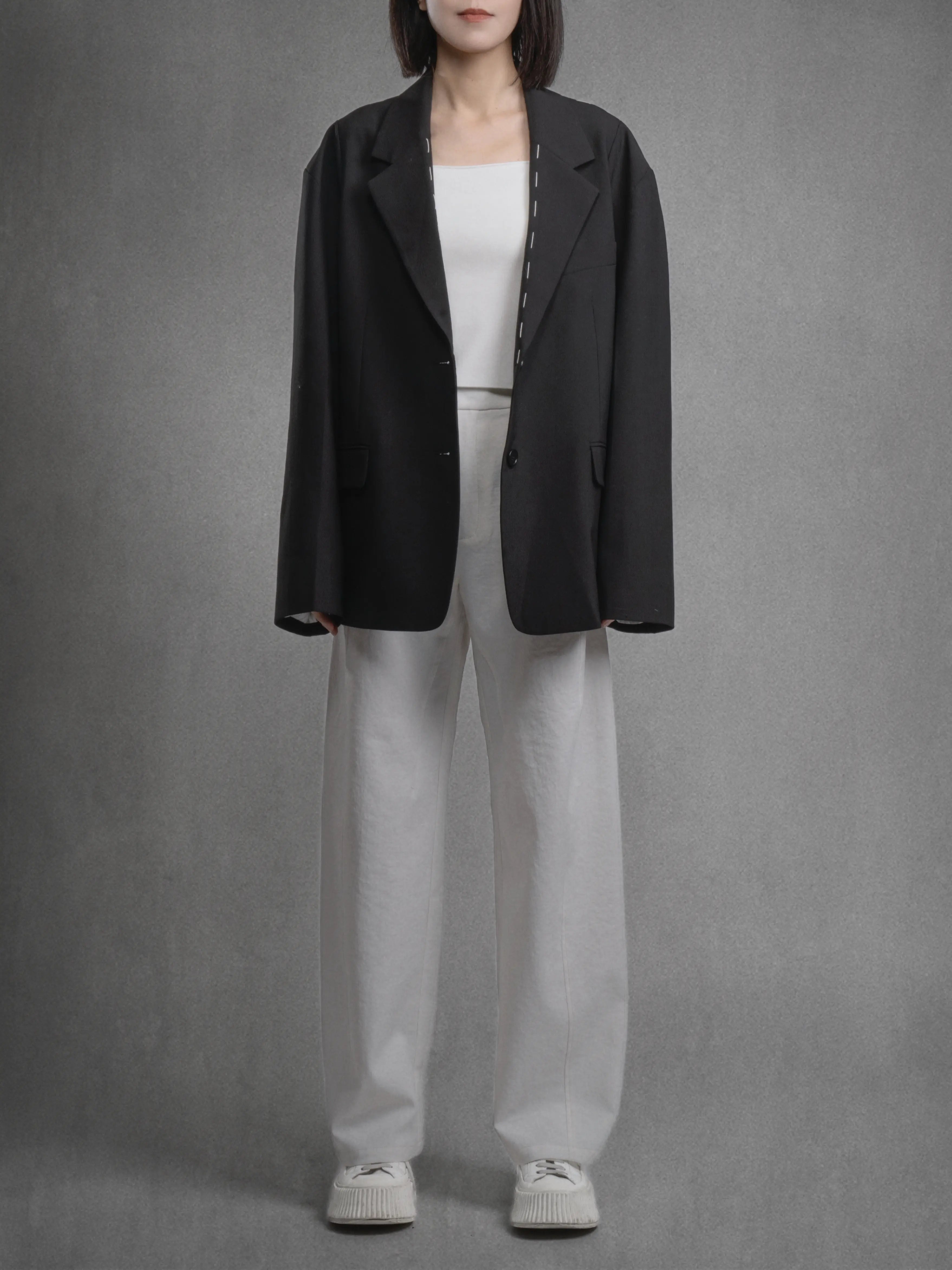 Charcoal blazer styled with white inner and light trousers, contrast look for casual office wear.