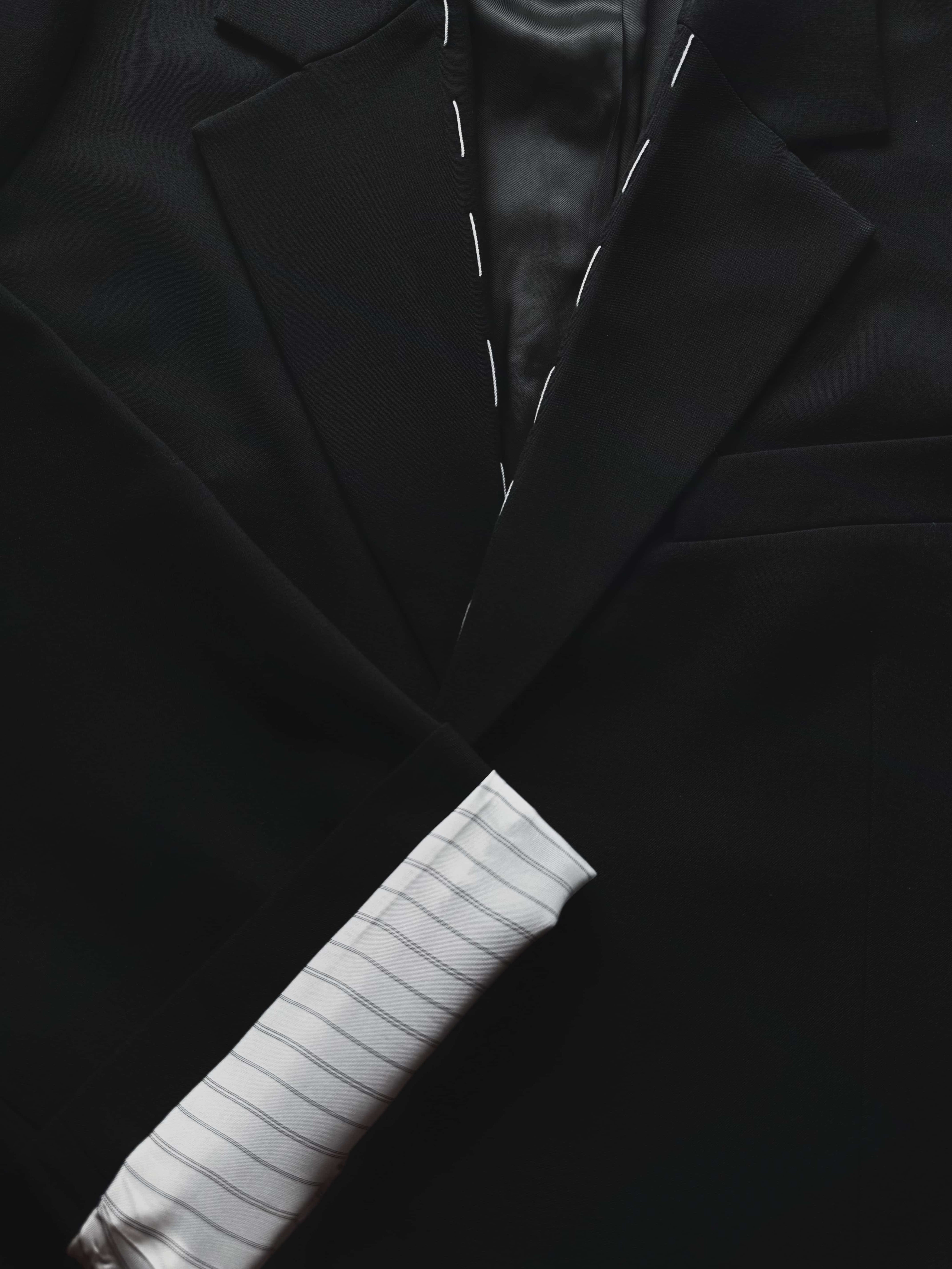 Close-up detail of blazer neckline and striped lining, rolled cuff and stitching visible.