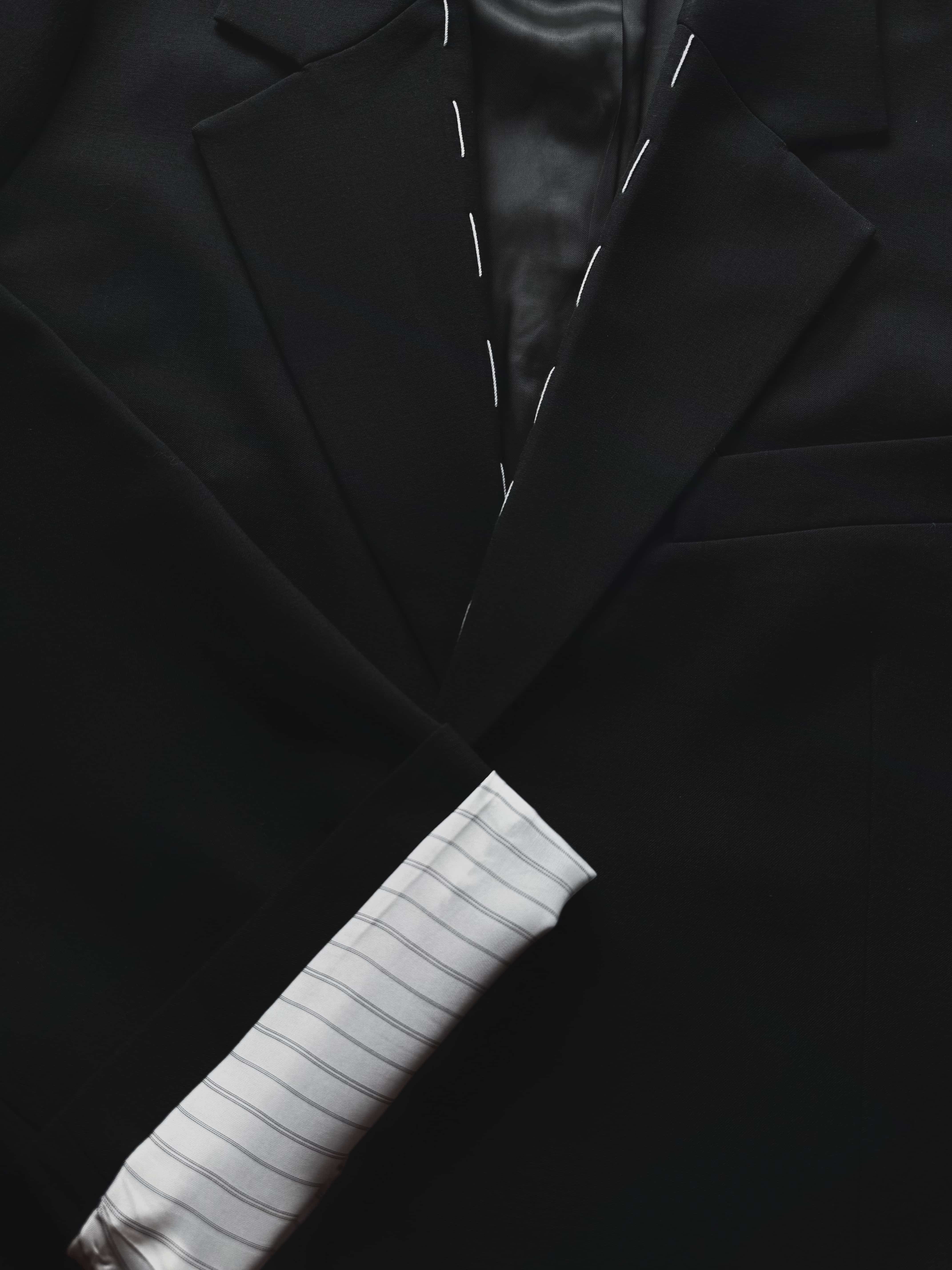 Close-up detail of blazer neckline and striped lining, rolled cuff and stitching visible.