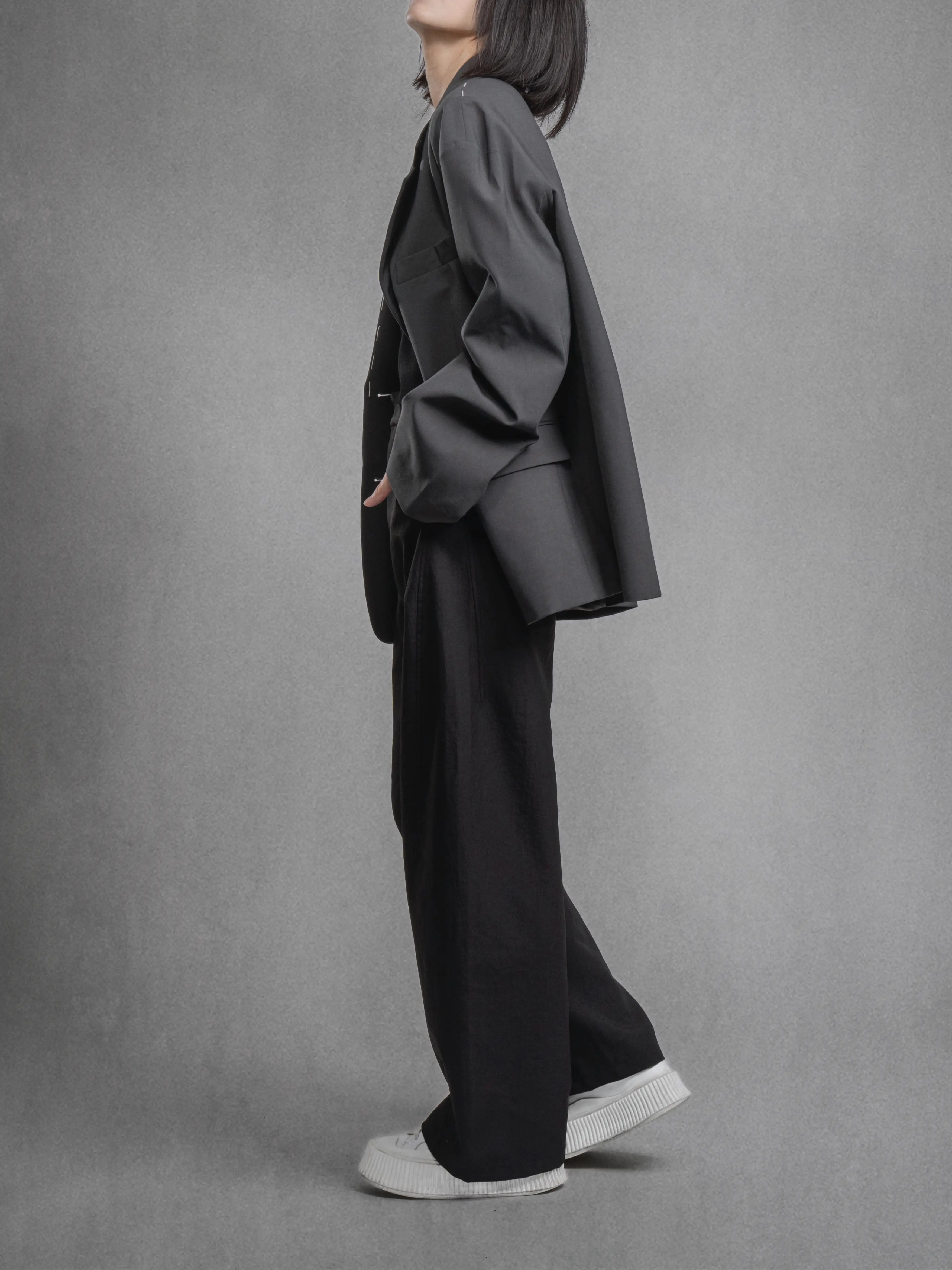 Relaxed blazer styling from angled side view, loose outline with rolled cuff detail.