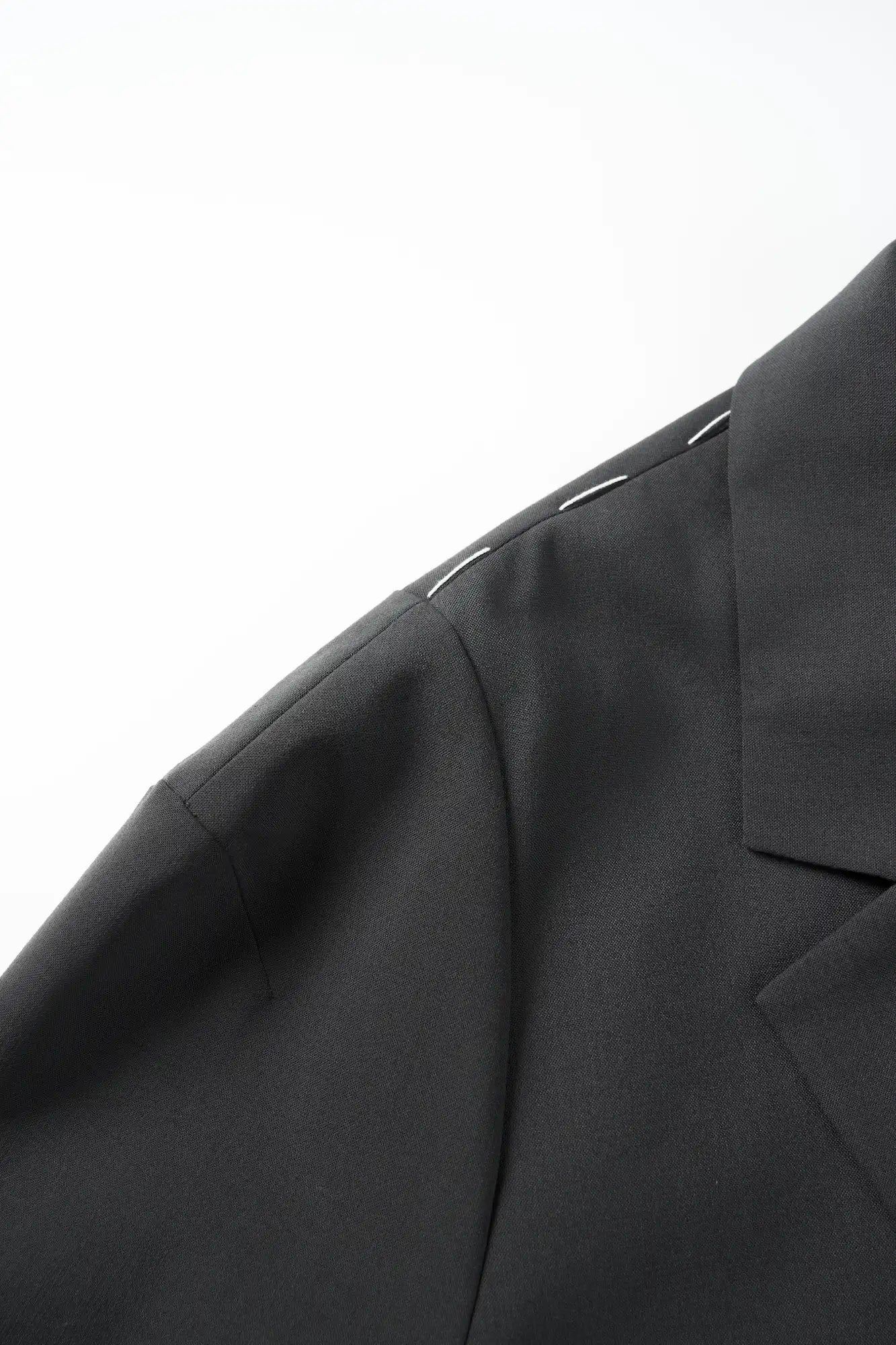 Detail shot highlighting the dropped shoulder construction and stitching quality of the charcoal blazer.