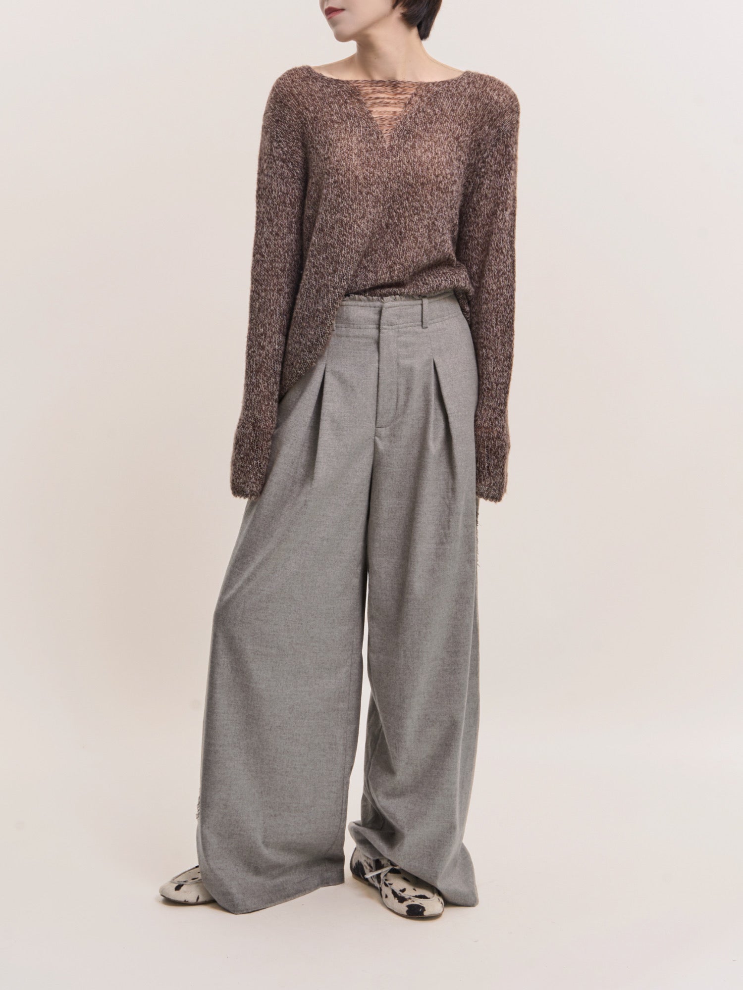 Model wearing grey Edge Wool Pants with wide-leg silhouette, full-body studio shot styled with textured brown knit.