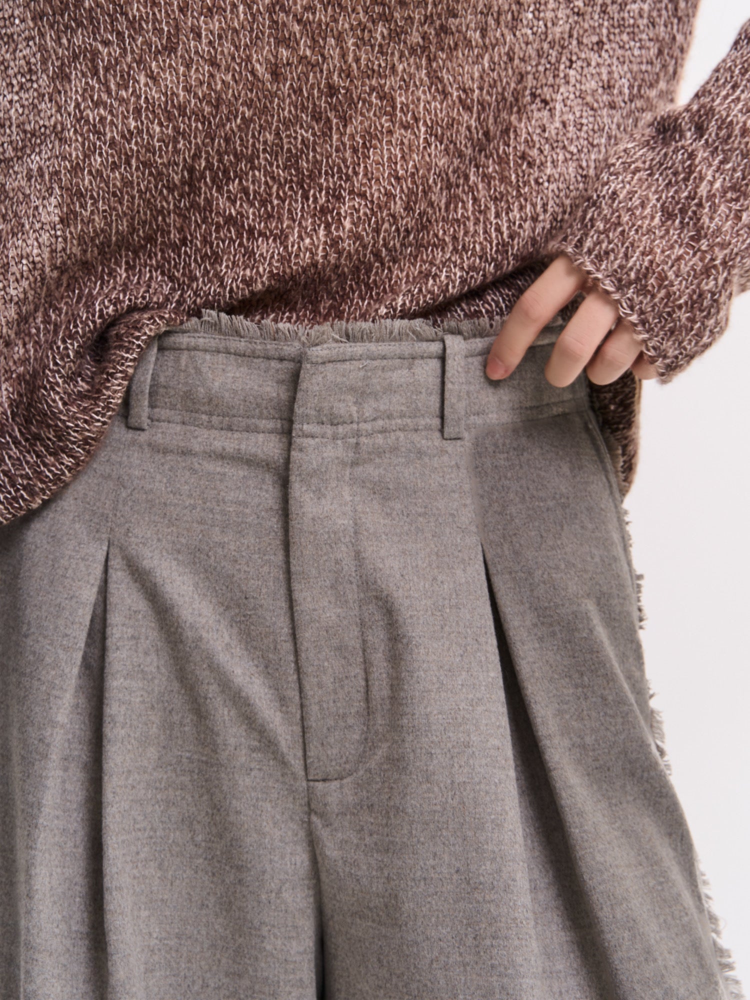Close-up waist detail of grey Edge Wool Pants showing pleats, clean stitching and soft structured fabric.