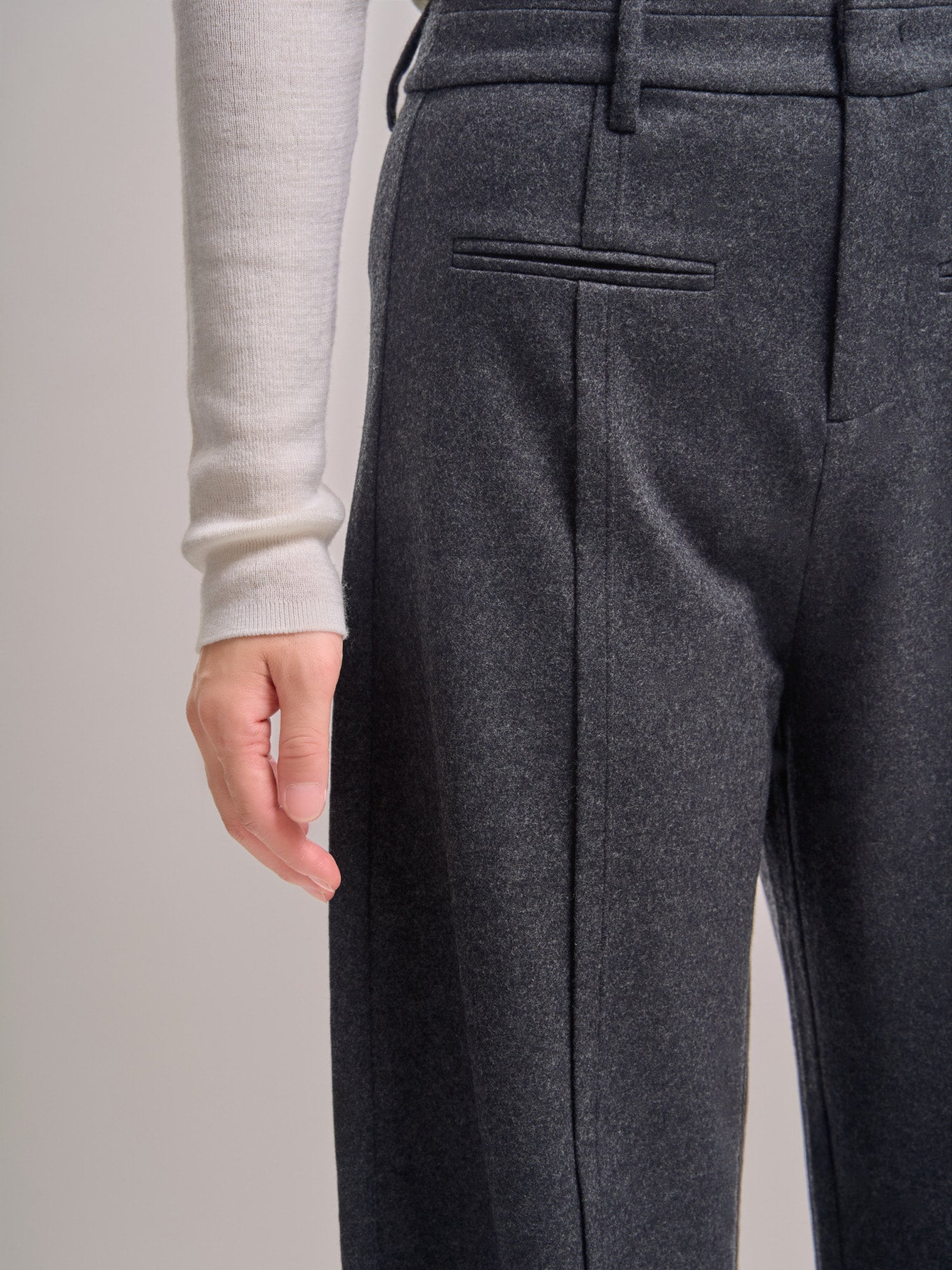 Close-up front detail of Minimalist Wool Pants, showing precise pleats and discreet welt pocket design.