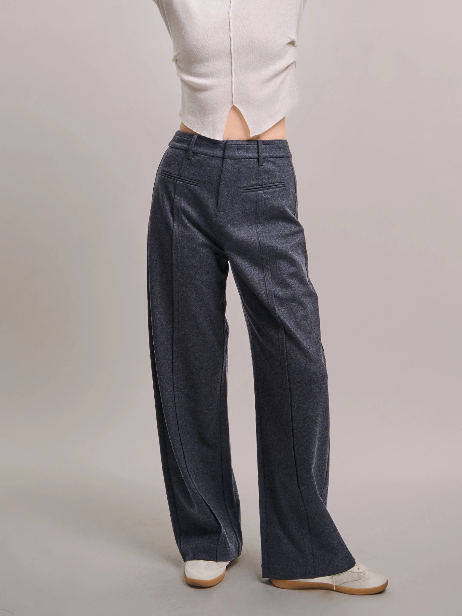 Model wearing charcoal grey Minimalist Wool Pants, full-body studio shot showing wide-leg silhouette and clean tailored line.