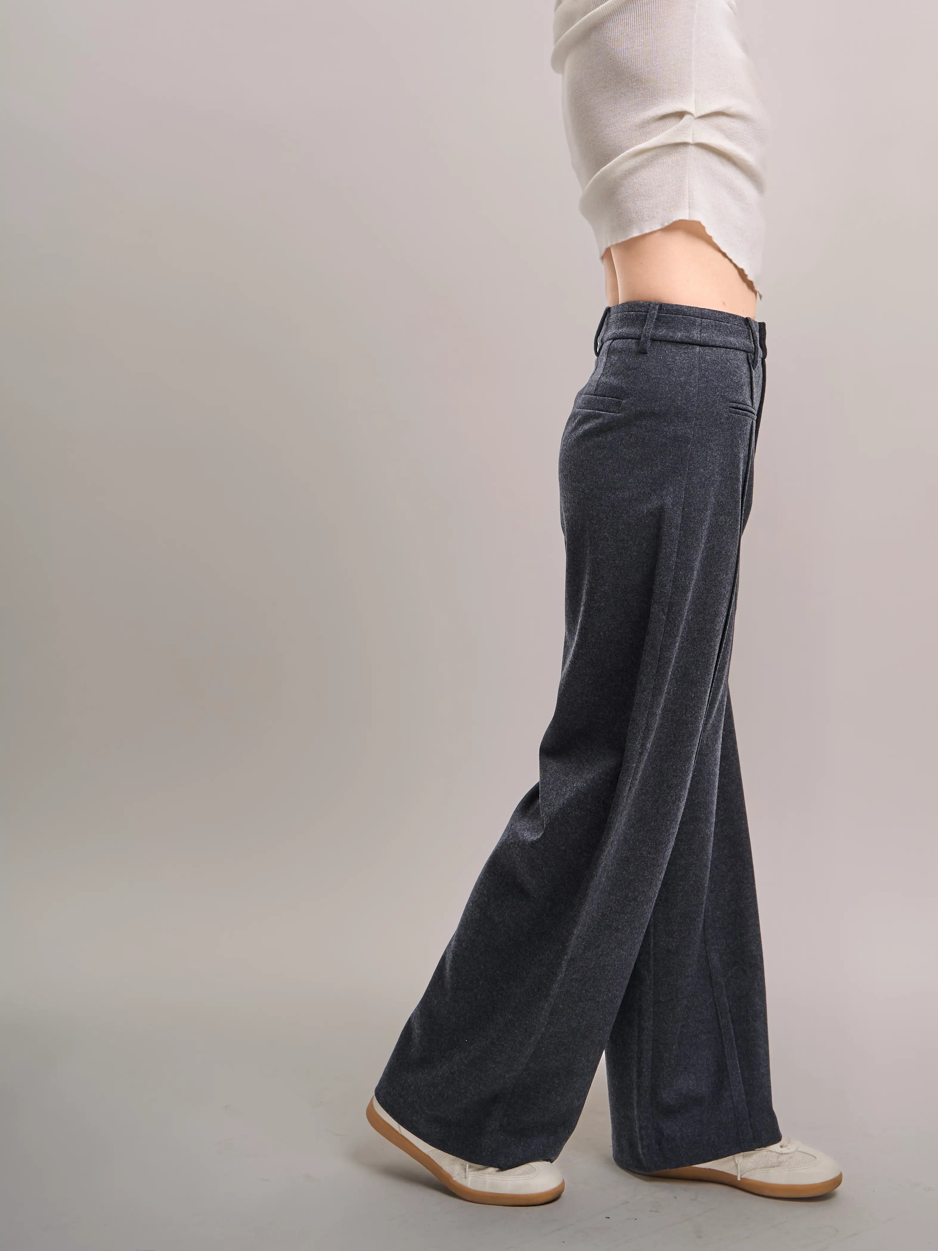 Side view of charcoal grey Minimalist Wool Pants highlighting wide-leg drape and smooth wool-rich texture.