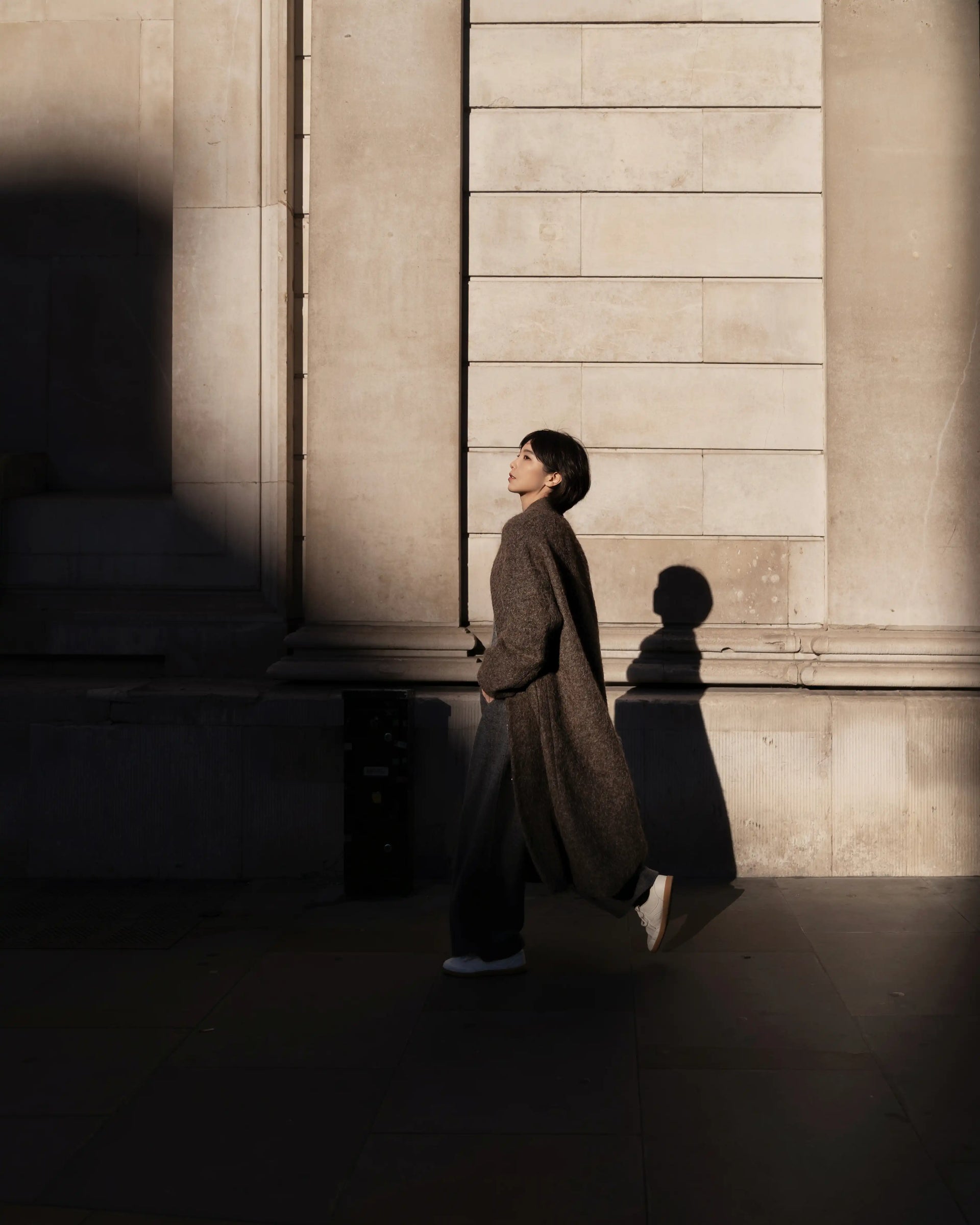 Woman wearing the Mocha Grace Wool Coat walking through an urban setting in natural light