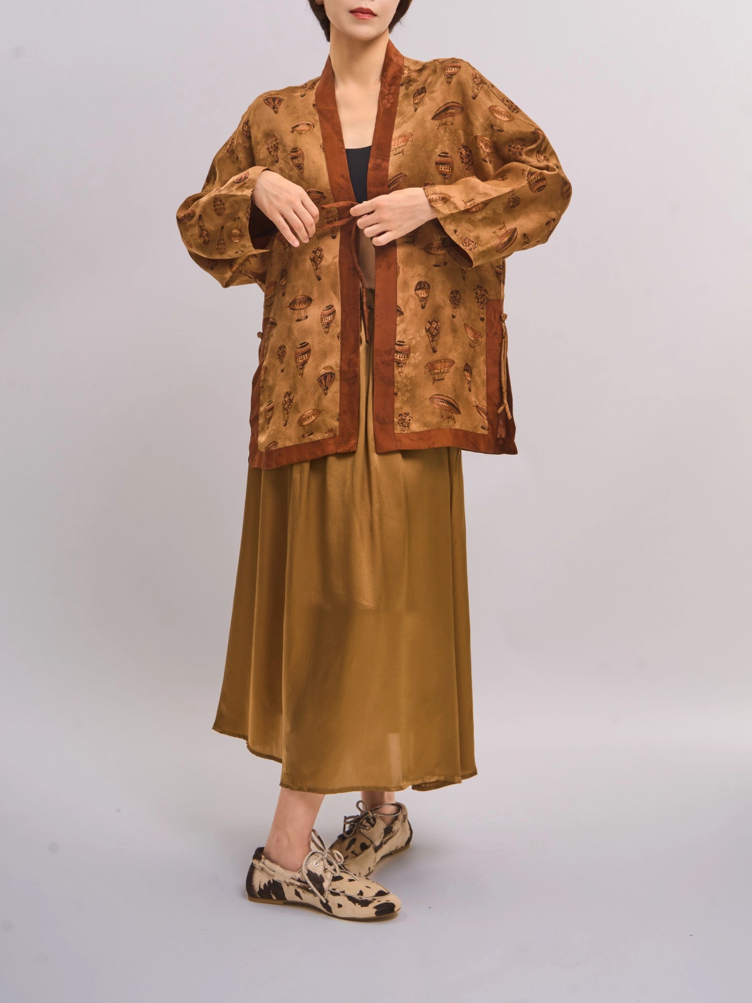 Model wearing bronze Xiangyunsha mulberry silk top, full-body studio shot showing fluid drape and open-front design.
