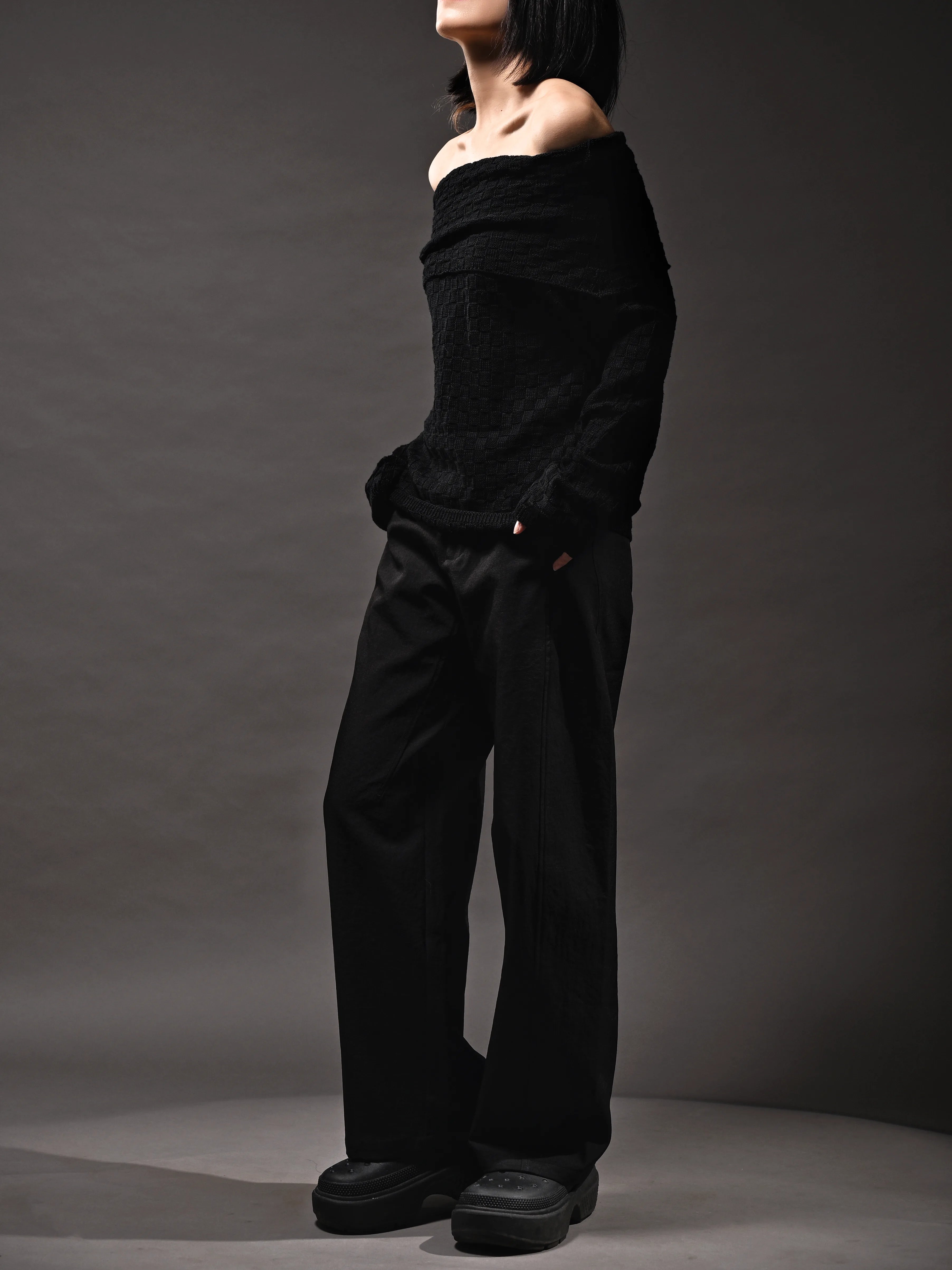 Black off-shoulder top side pose, slim neckline framing shoulders, modern monochrome look.