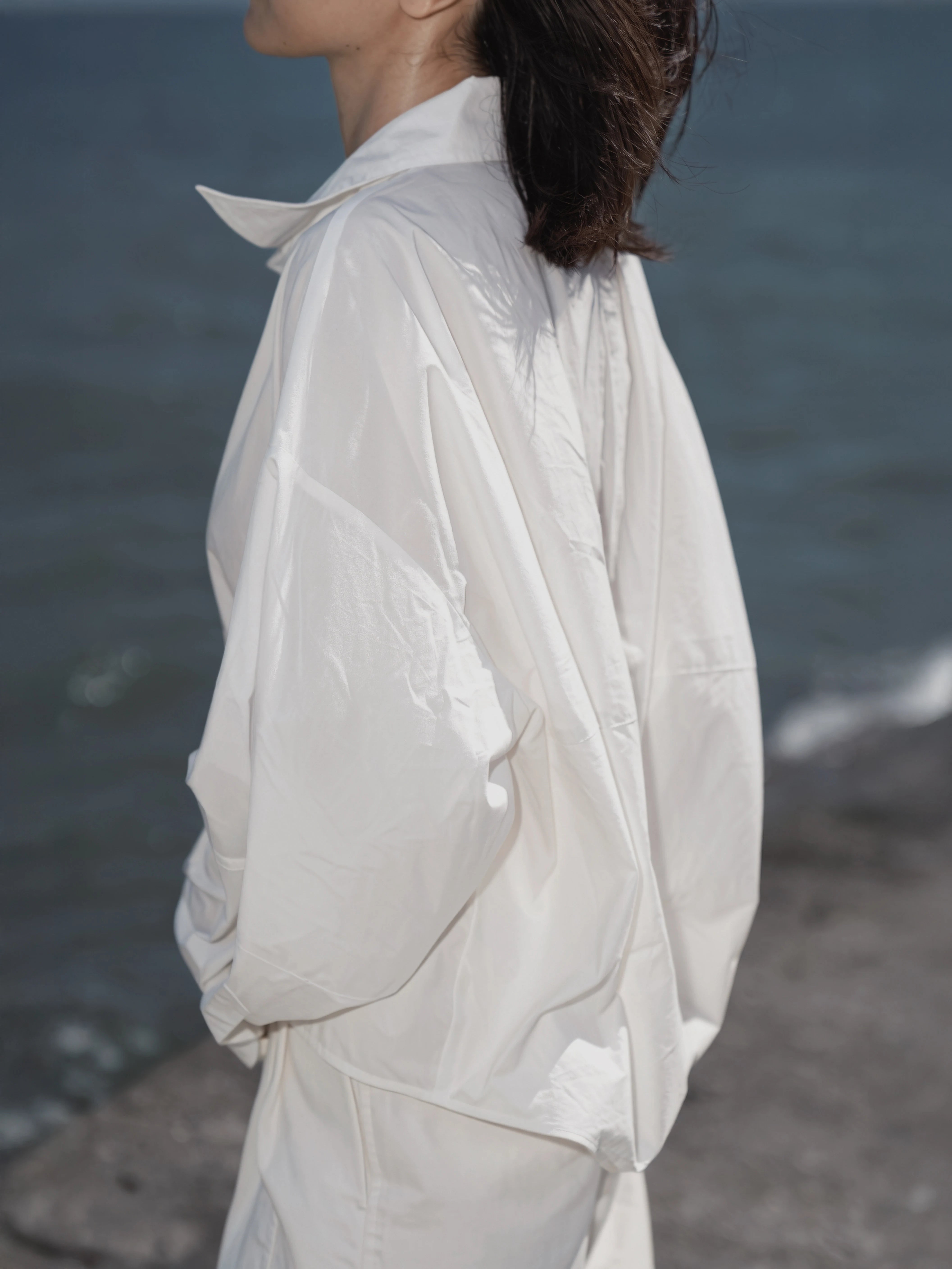 Back view of the Pima Boxy Shirt in white at the seaside.