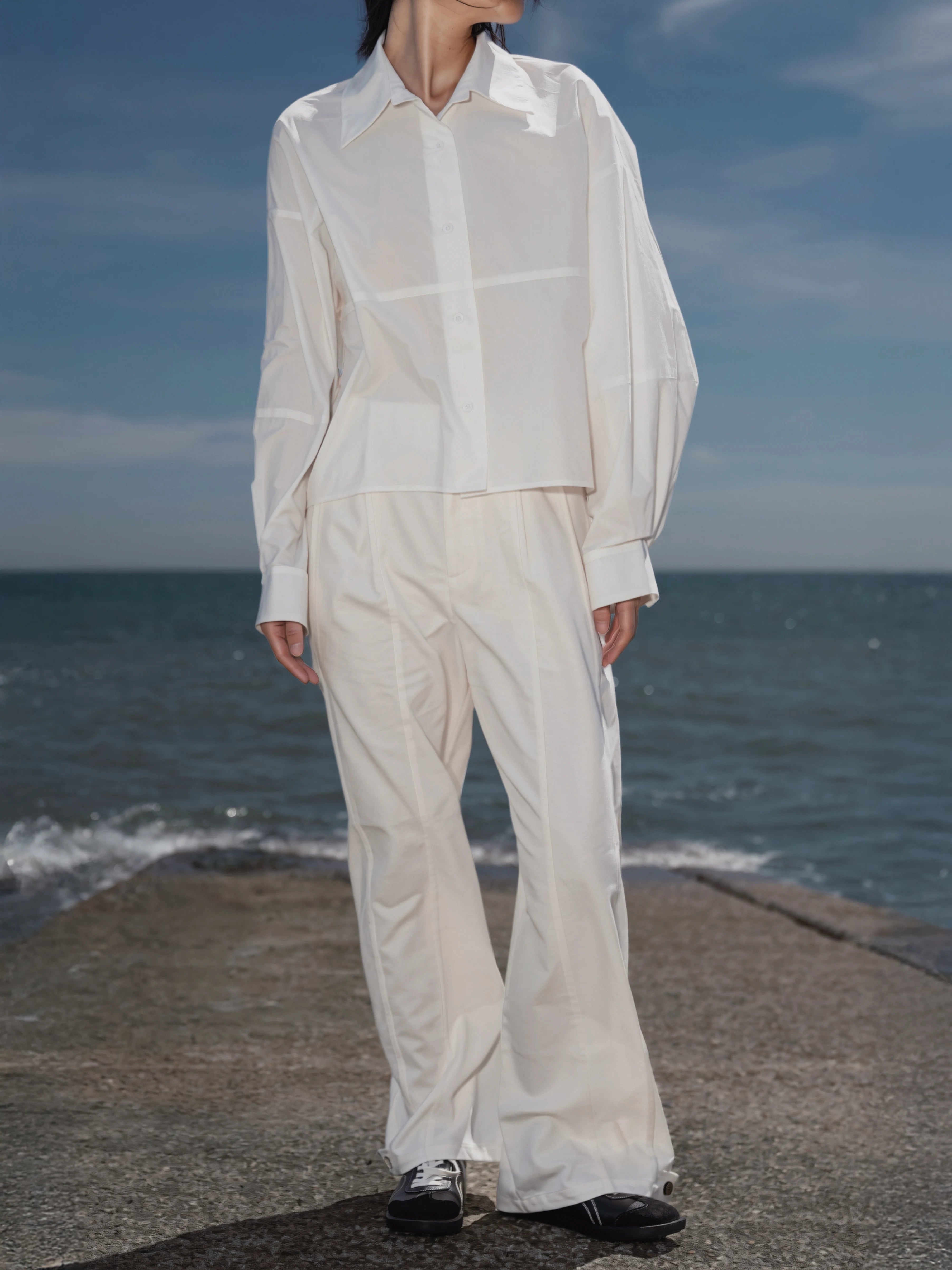 Model wearing the Pima Boxy Shirt in Soft Cream by the seaside.