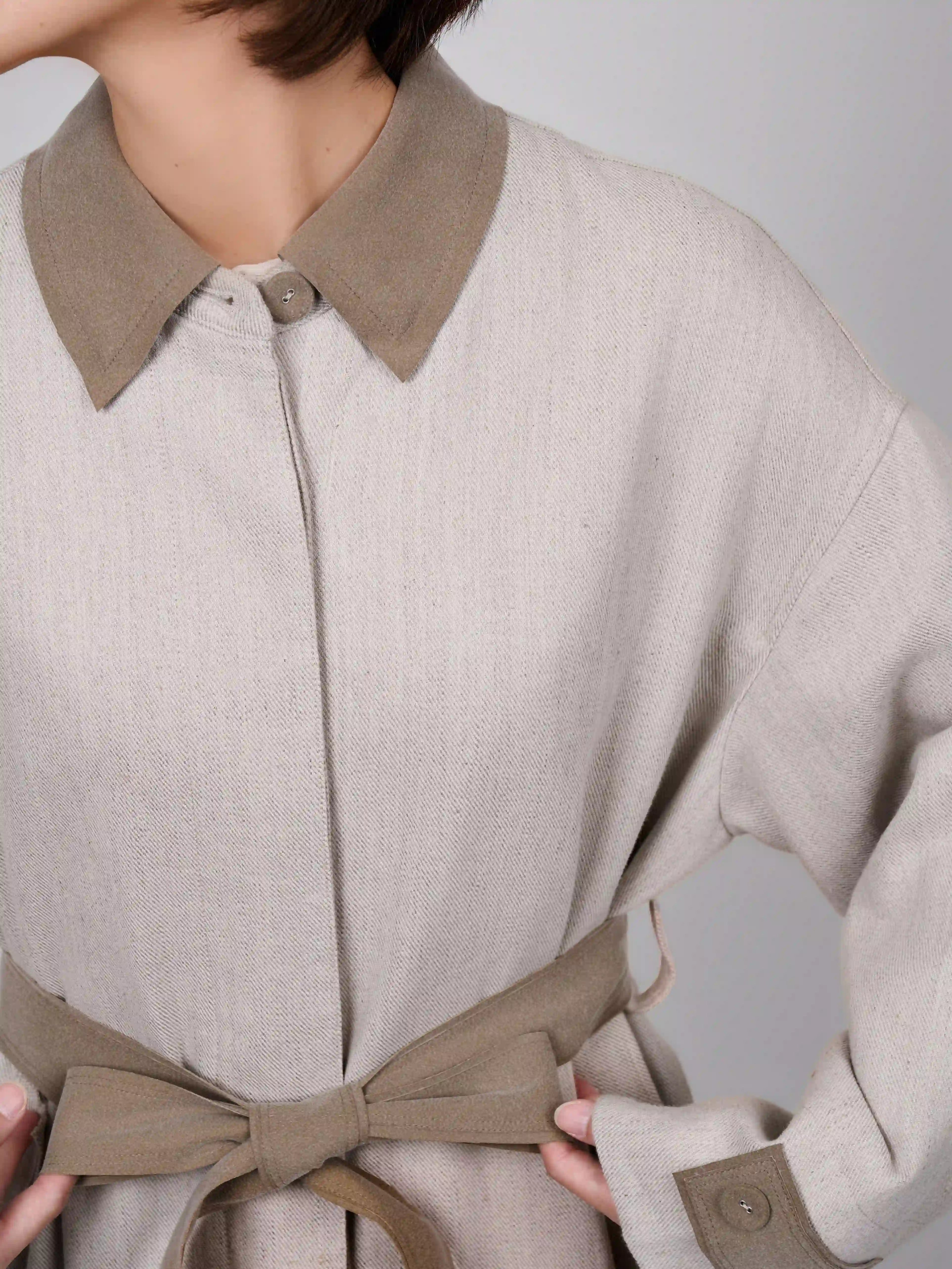Collar and waist belt detail of XXLsmile beige linen wool coat highlighting soft structure and refined stitching