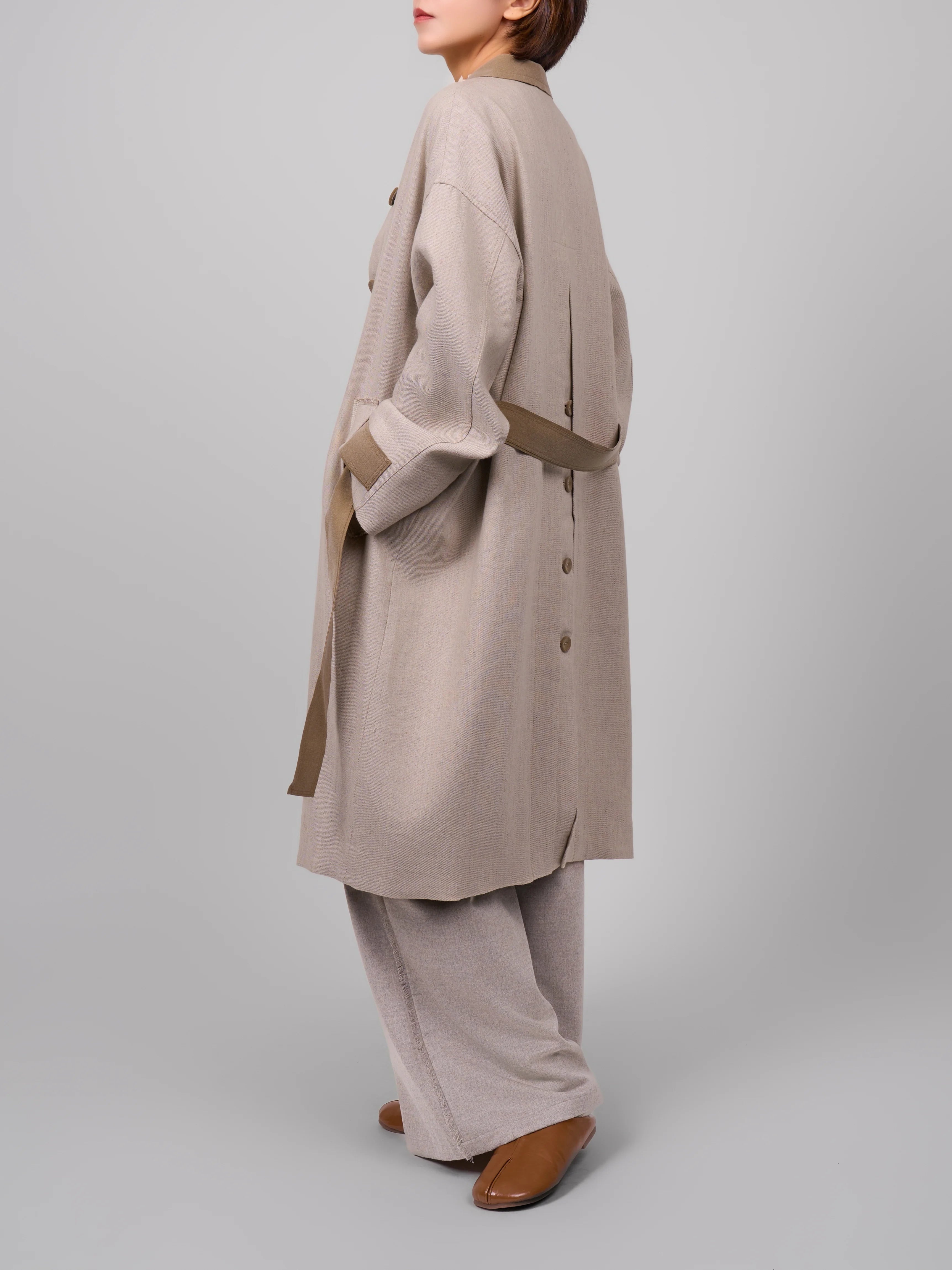Side view of beige Rain Dew linen–wool coat, showing cocoon back line and easy movement over trousers.