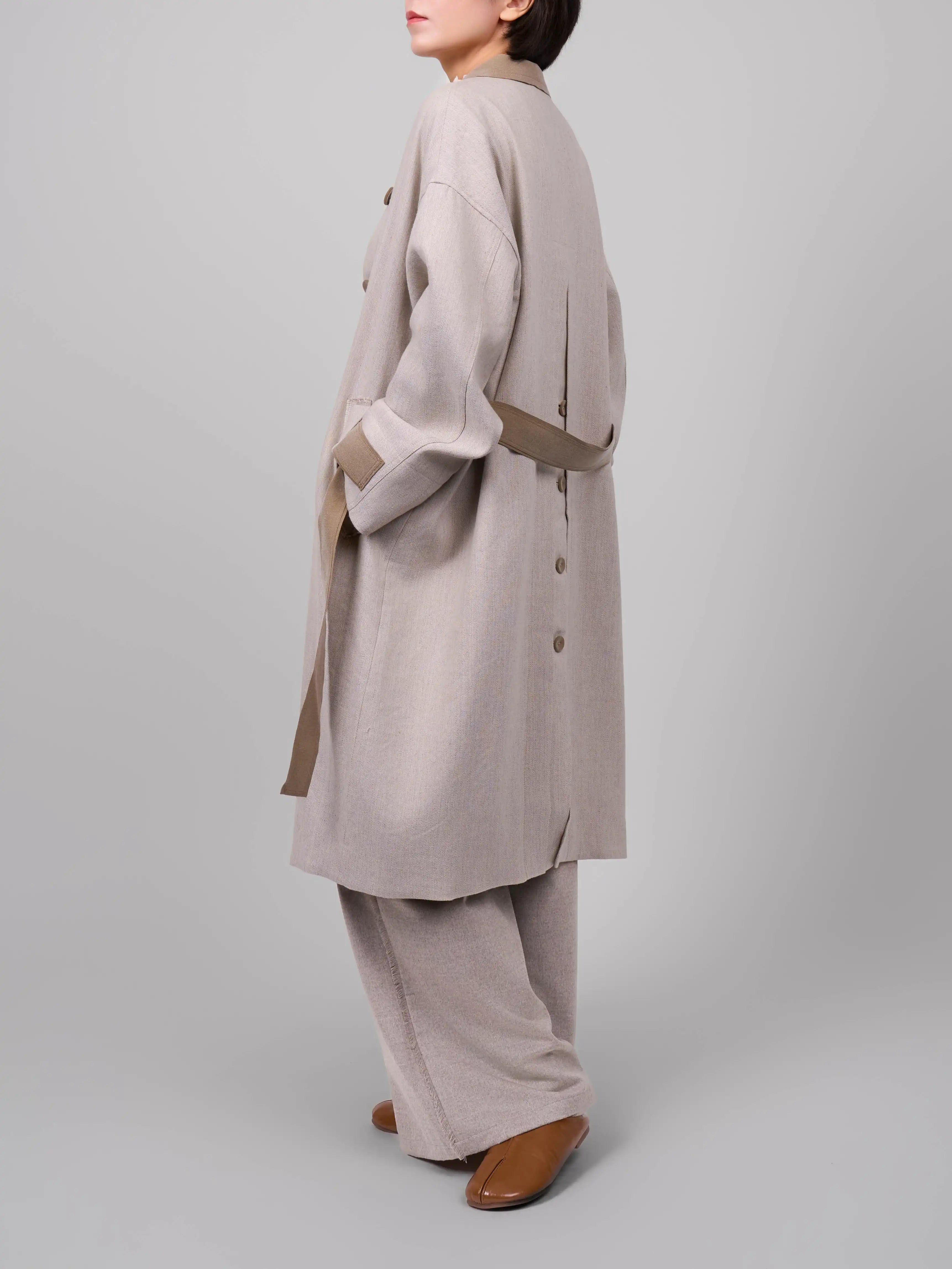 Side walking view of beige rain dew linen wool coat by XXLsmile showing fluid silhouette and lightweight structure