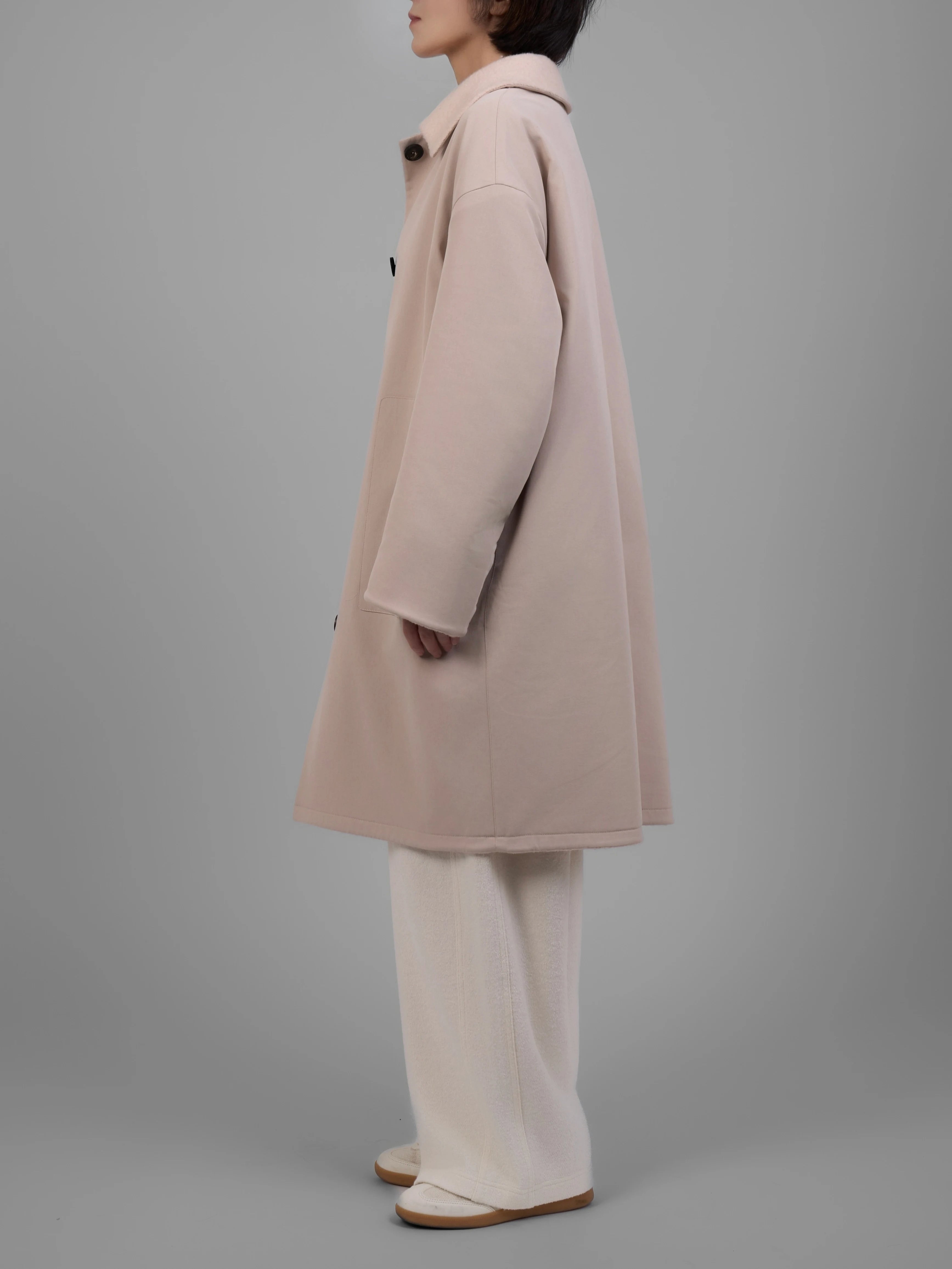 Reversible cream wool coat captured in angled back view highlighting straight back panel.