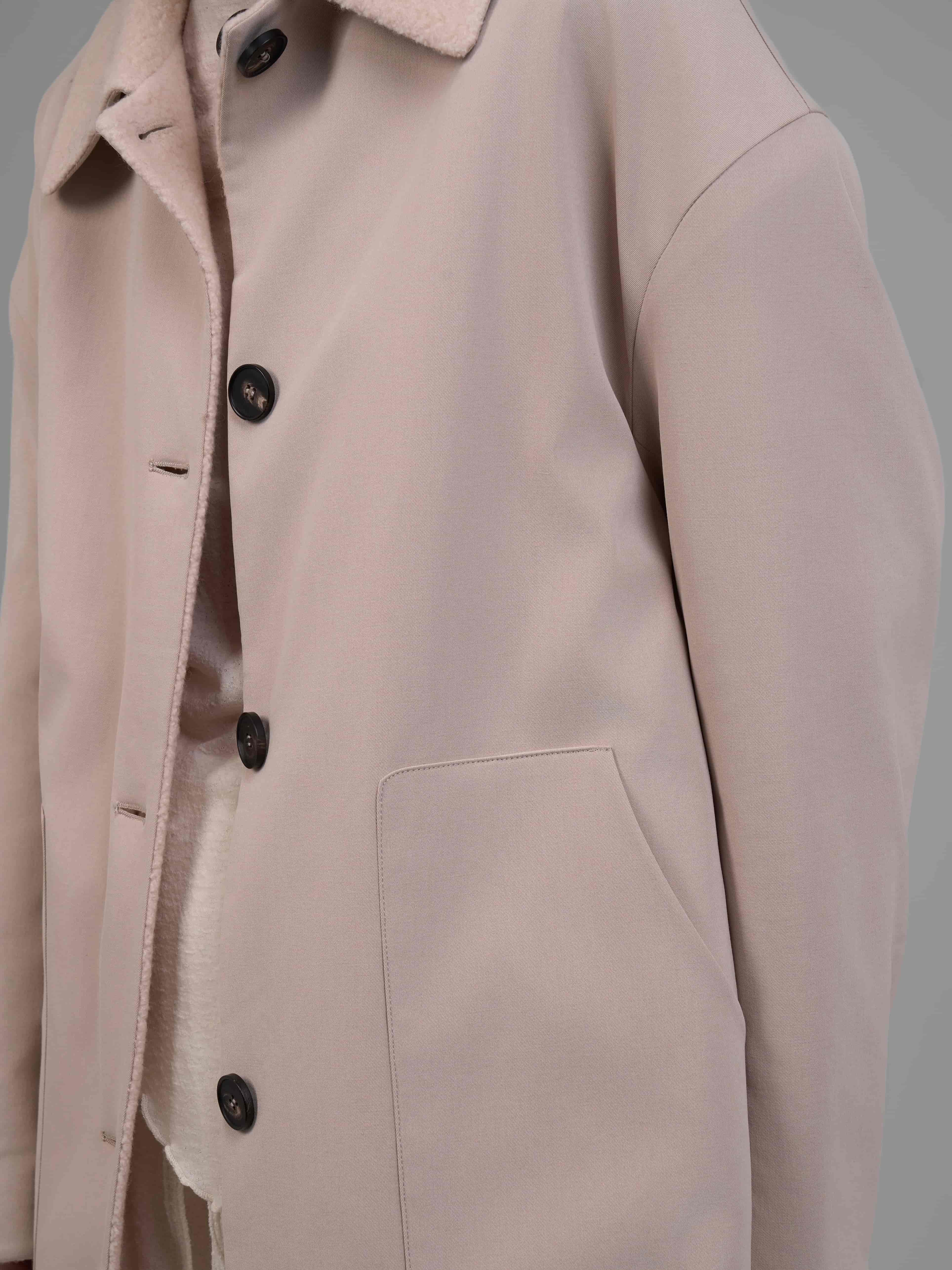 Fabric close-up of reversible cream wool coat showing soft woven texture.