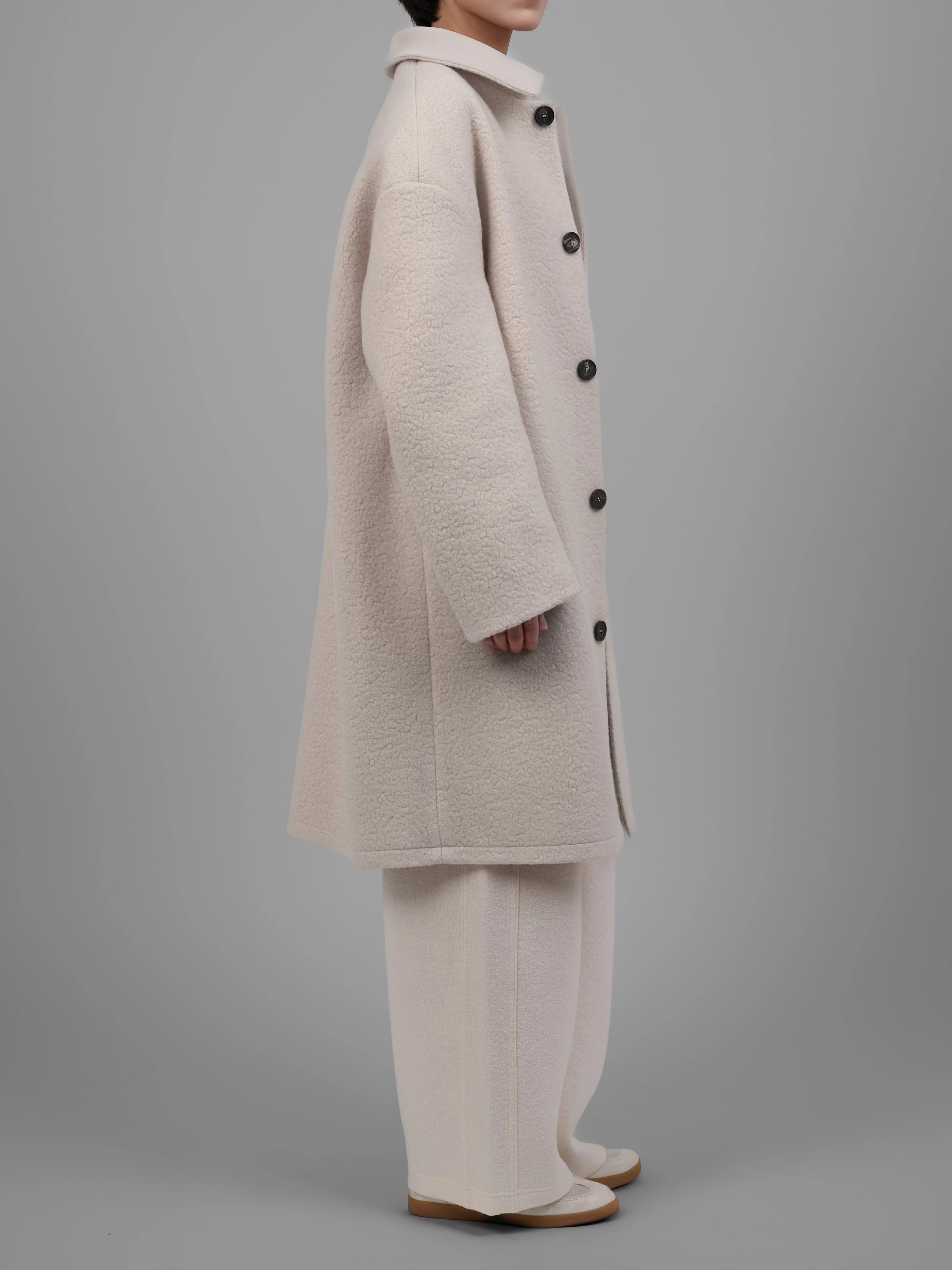 Side profile view of XXLsmile cream reversible wool coat showing relaxed silhouette and clean tailoring