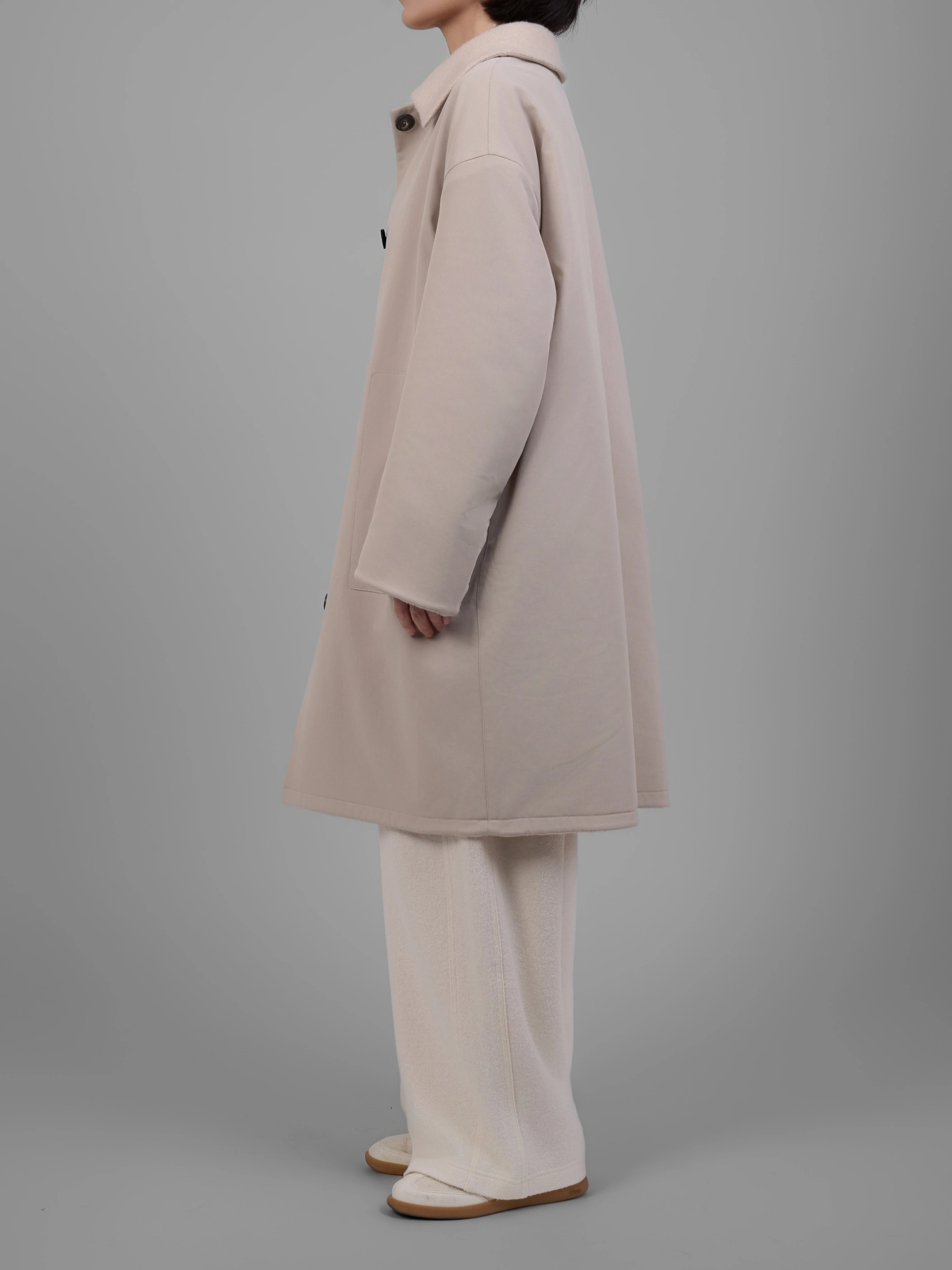 Three quarter side view of XXLsmile cream wool reversible coat highlighting soft structure and length