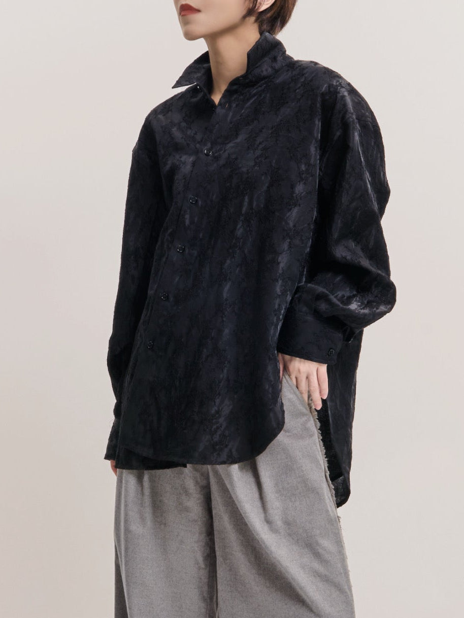 Model wearing black textured shirt with grey wide-leg trousers, full-body studio shot showing cocoon silhouette.