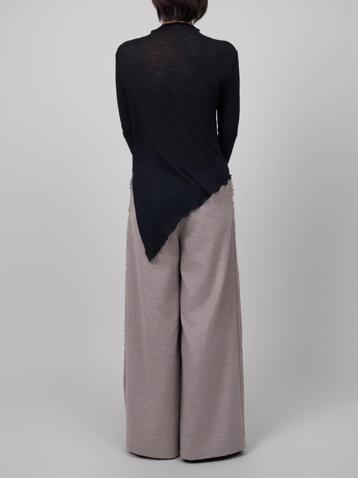 Back view of black wool base layer, showing sheer texture and clean raw-edge finish.