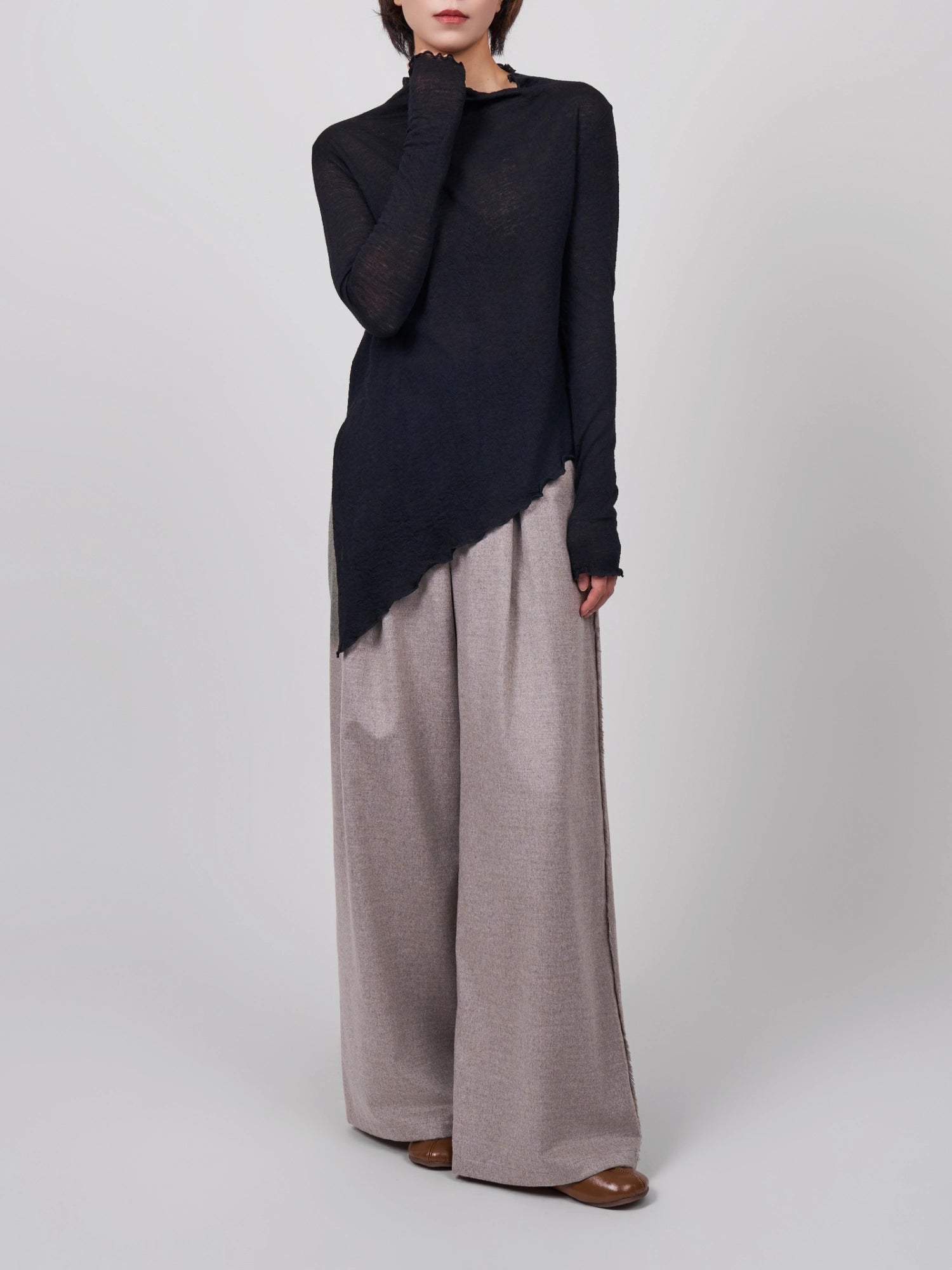 Front view of black wool base layer showing elongated asymmetric silhouette and lightweight drape.