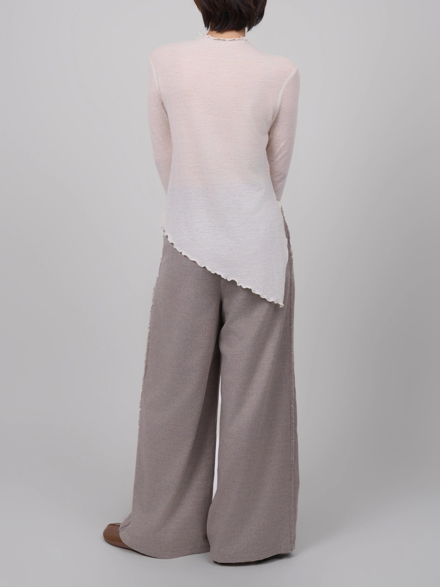 Back view of white wool base layer, showing elongated asymmetric silhouette and lightweight wool drape.