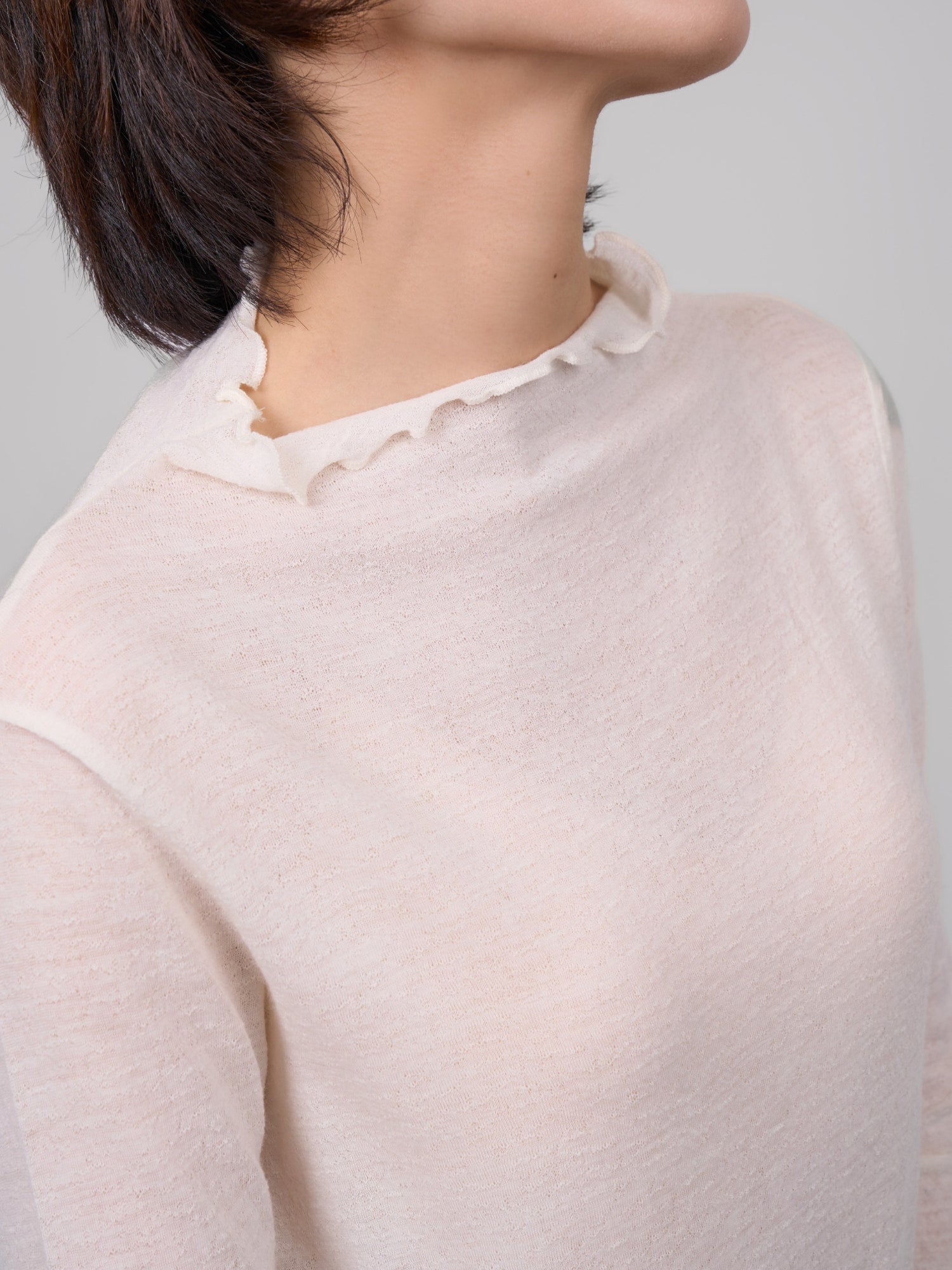 Front close-up of white wool base layer showing raw-edge collar and fine natural wool texture.