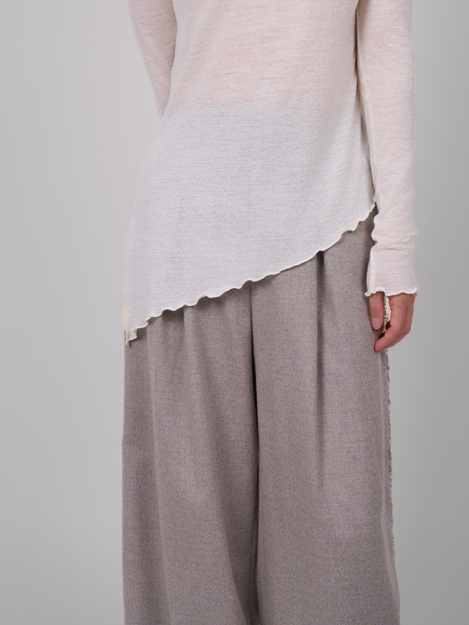 Side view of white wool base layer highlighting asymmetric hem and breathable sheer knit texture.