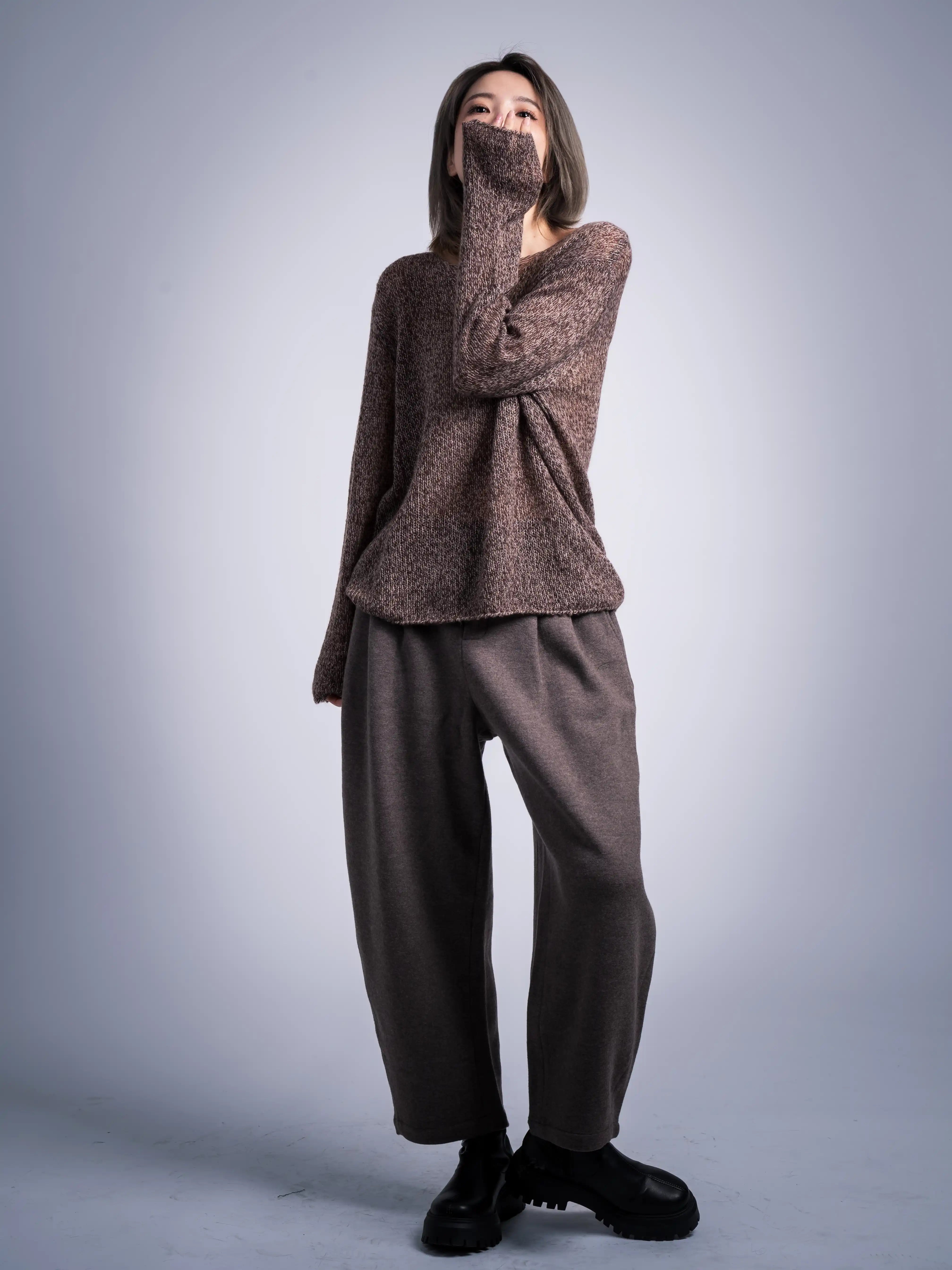 Full-length outfit shot of wool jumper with wide trousers, minimal monochrome styling in grey-brown palette.