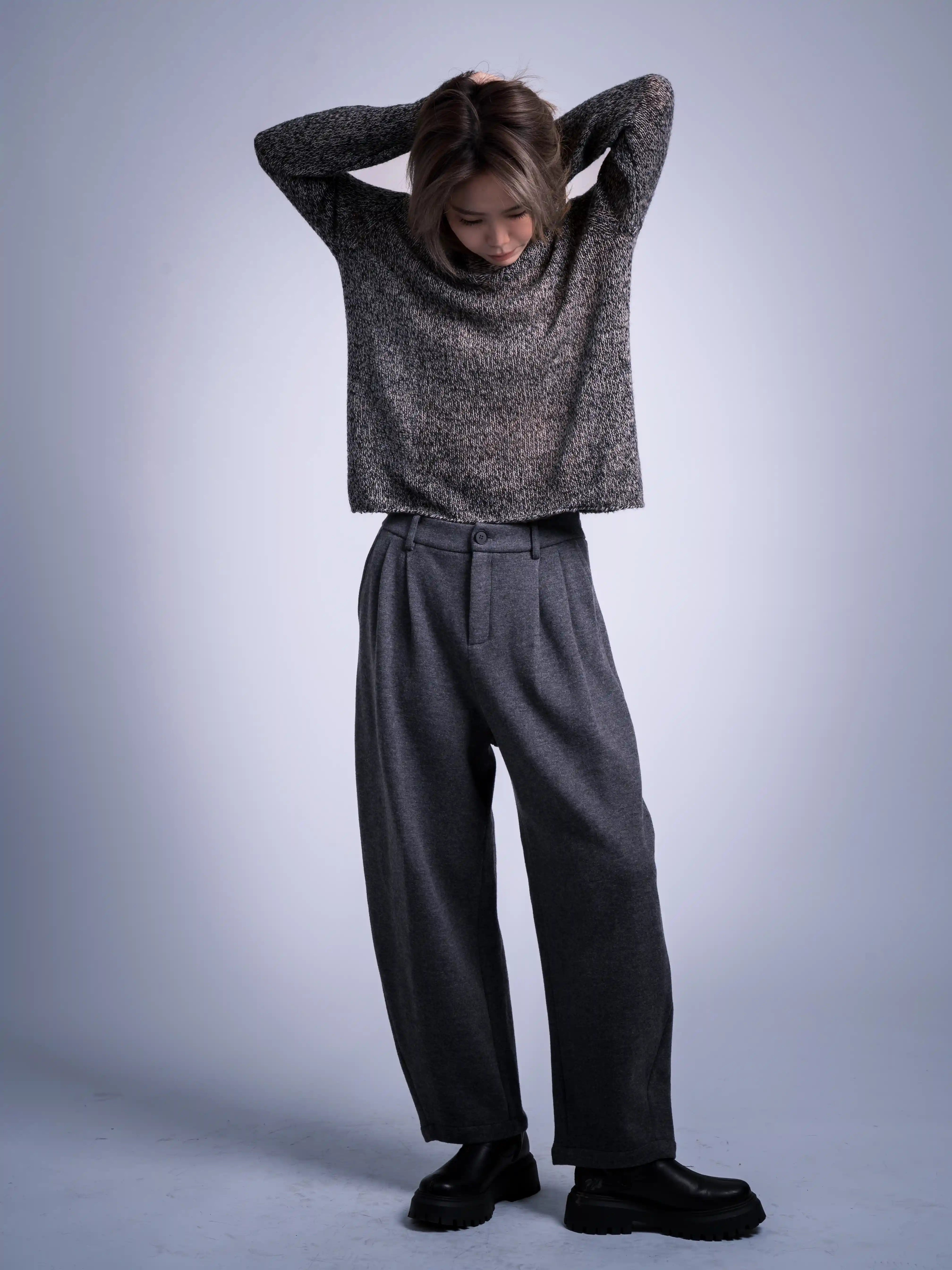 Loose brown wool jumper, casual pose with hands behind head, soft texture shown under neutral studio light.