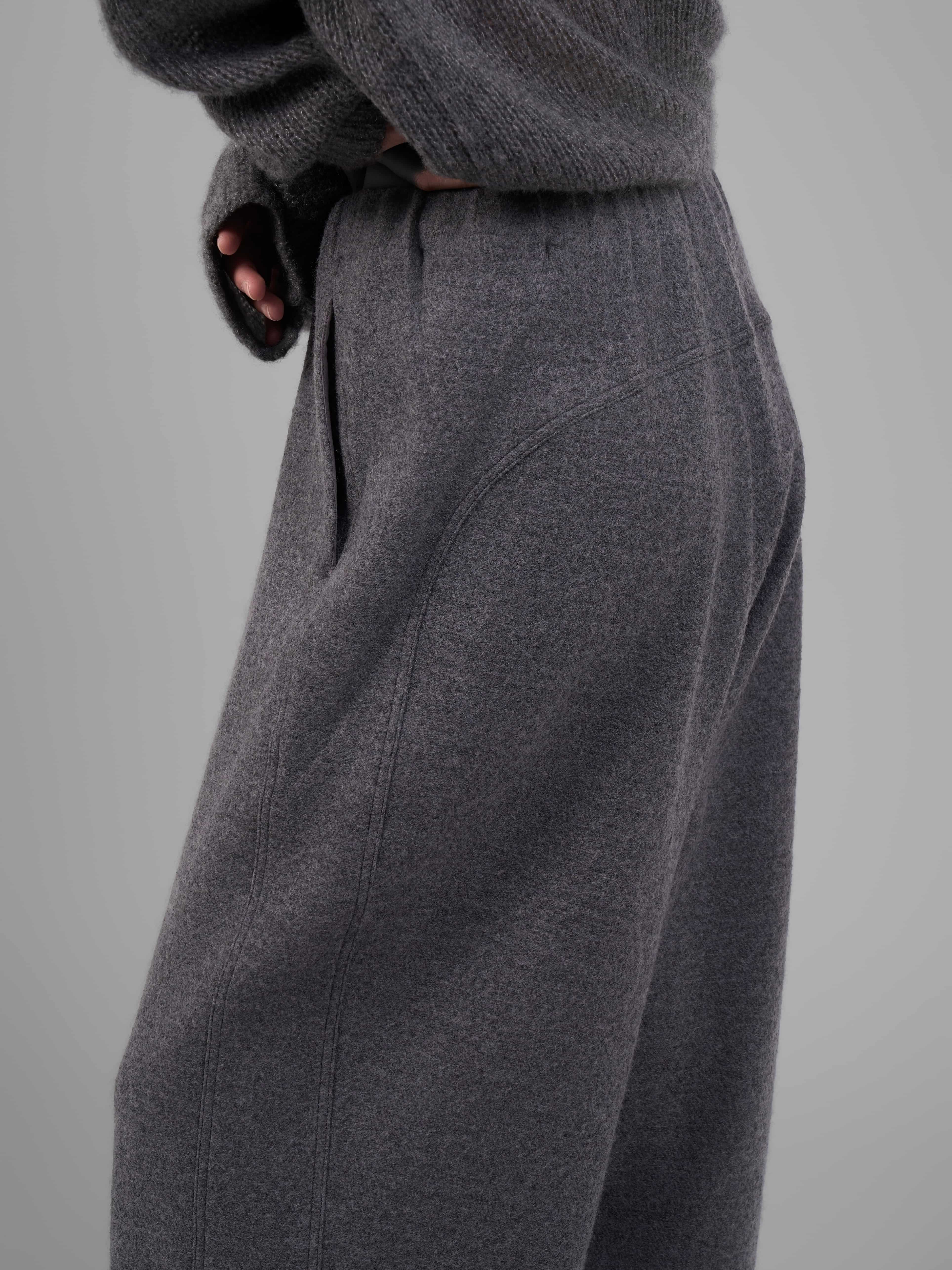 Close-up side detail of grey wool-blend knit trousers showing waistband texture.