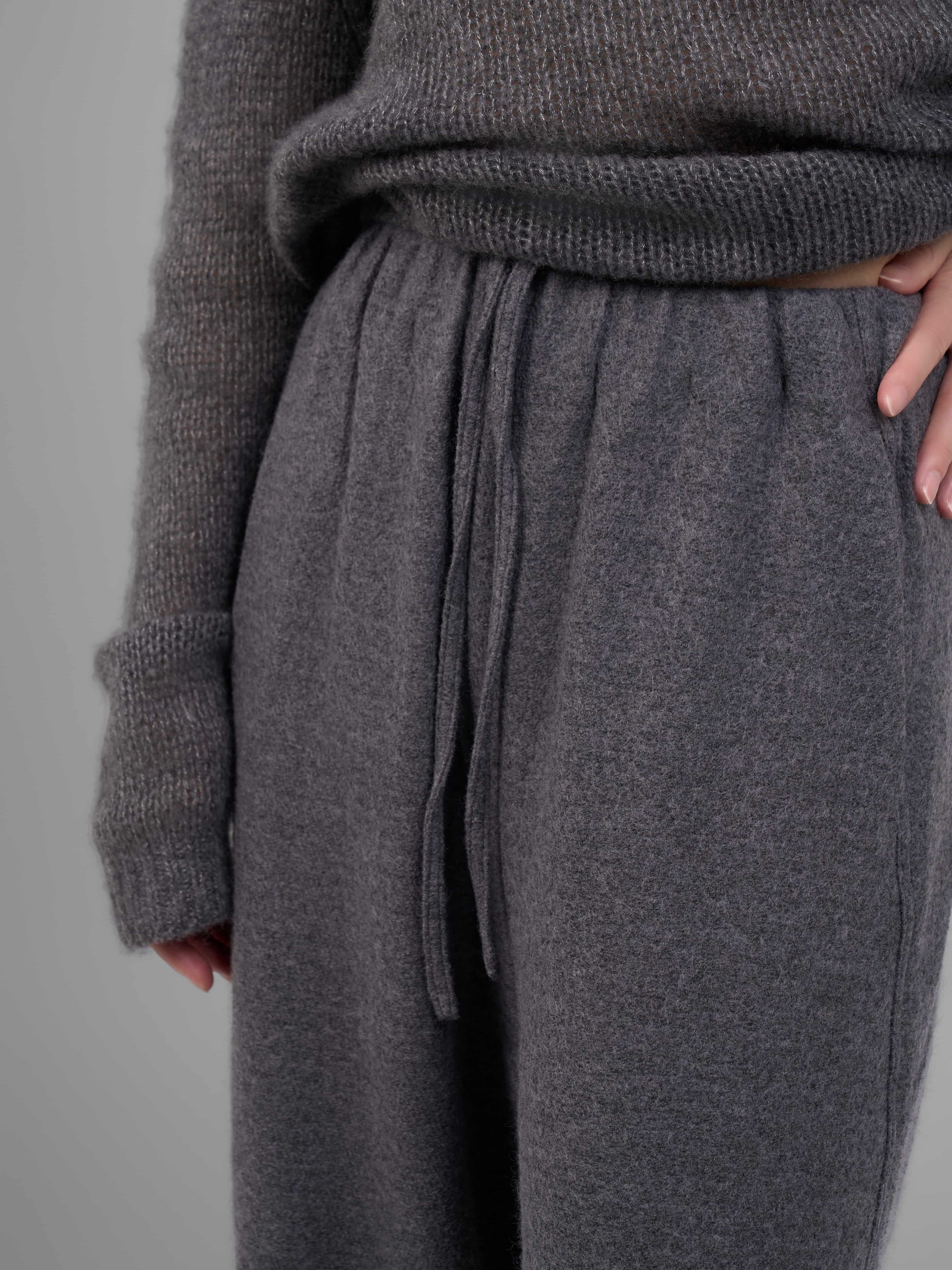 Grey wool-blend knit trousers waistband and pocket detail close-up.