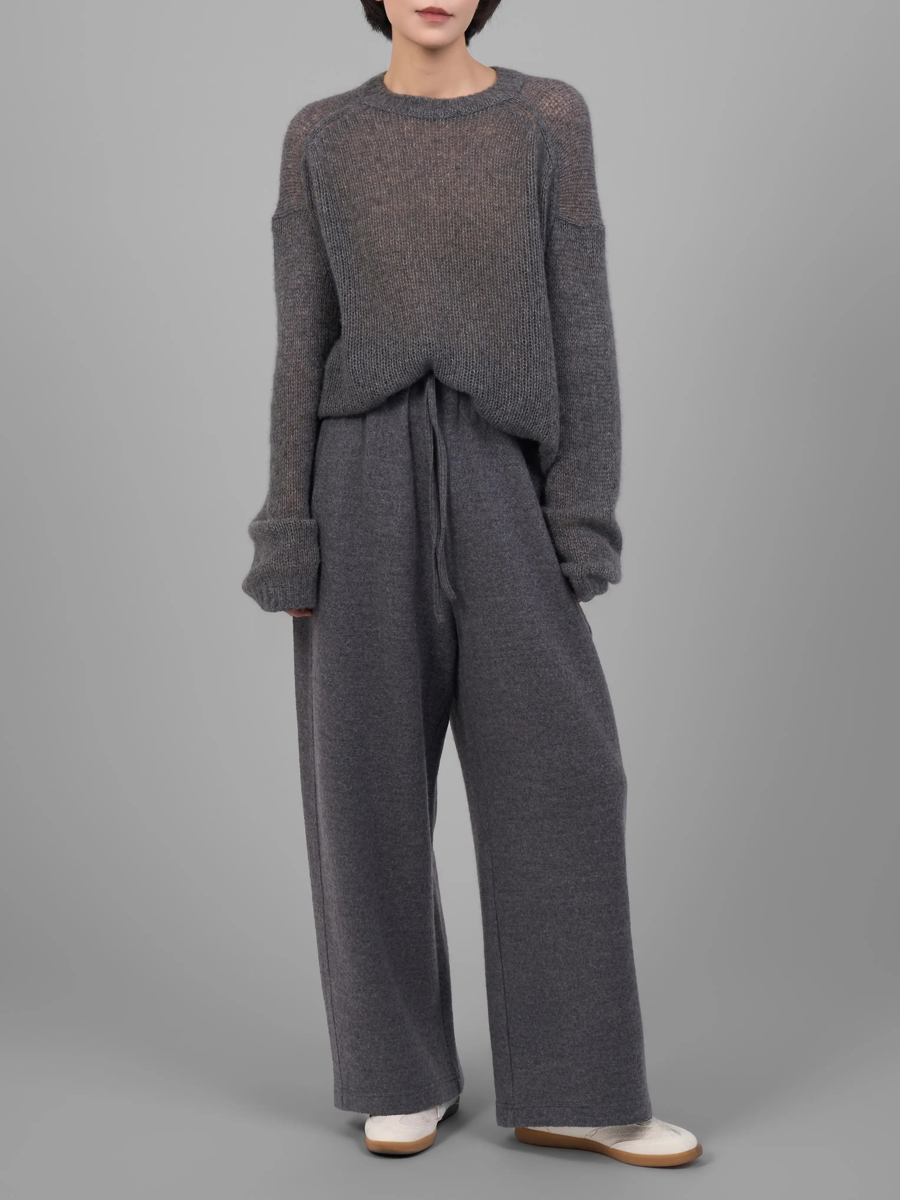 Grey wool-blend knit trousers styled with matching knit top in studio full-body look.