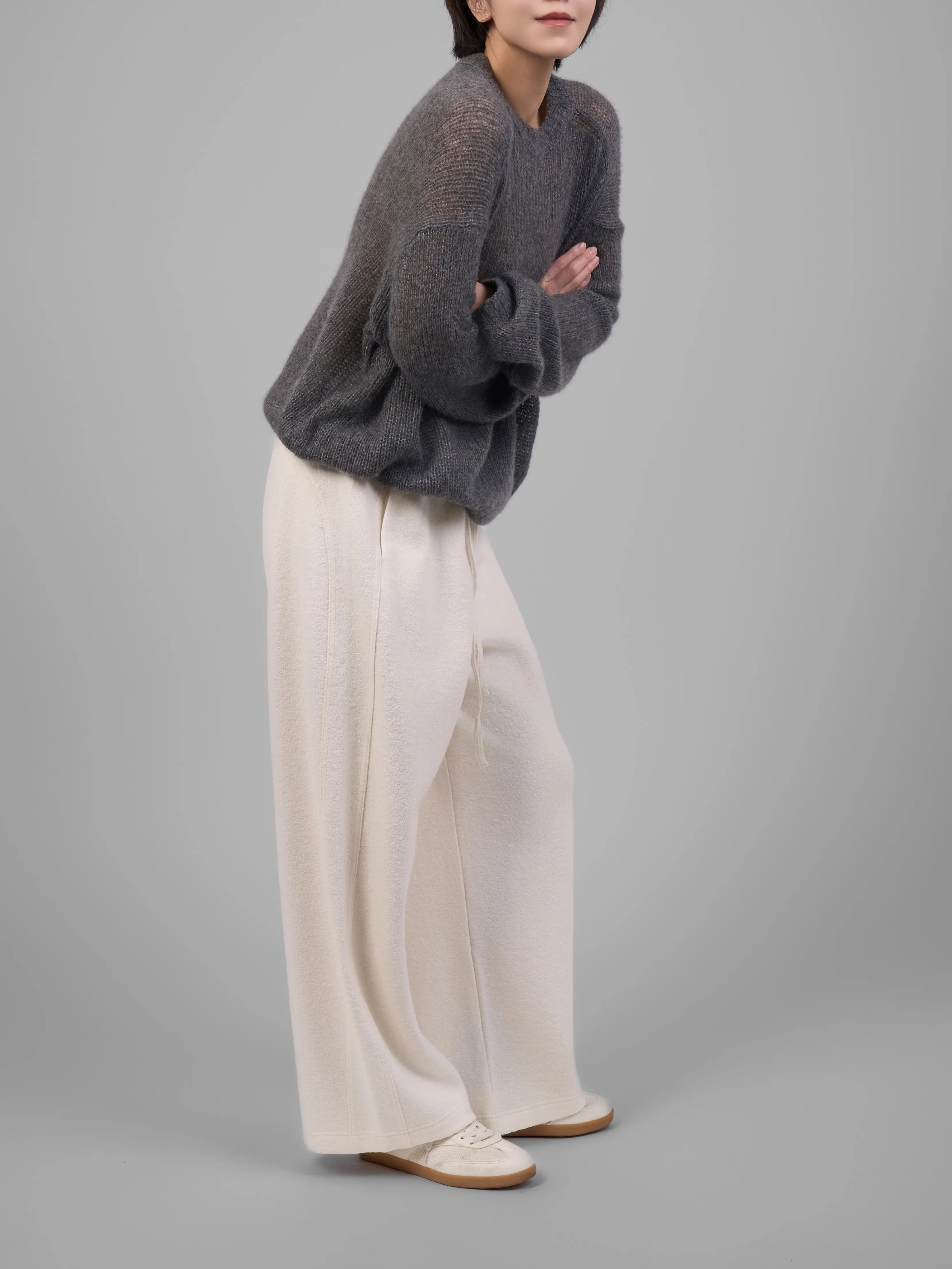 Grey wool-blend knit trousers styled with white trousers, side walking pose.