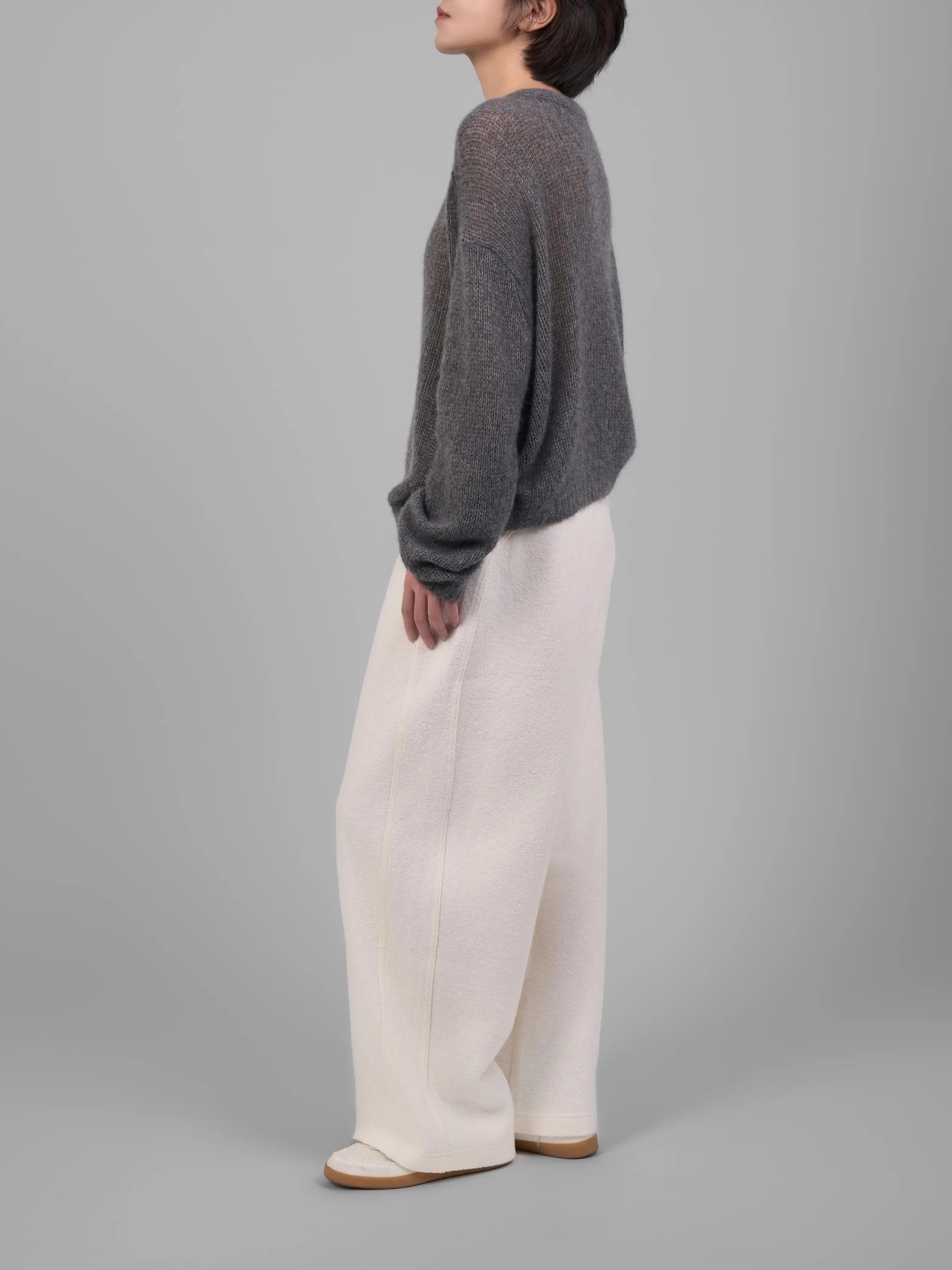 Grey wool-blend knit trousers styled with white trousers, minimal studio outfit shot.