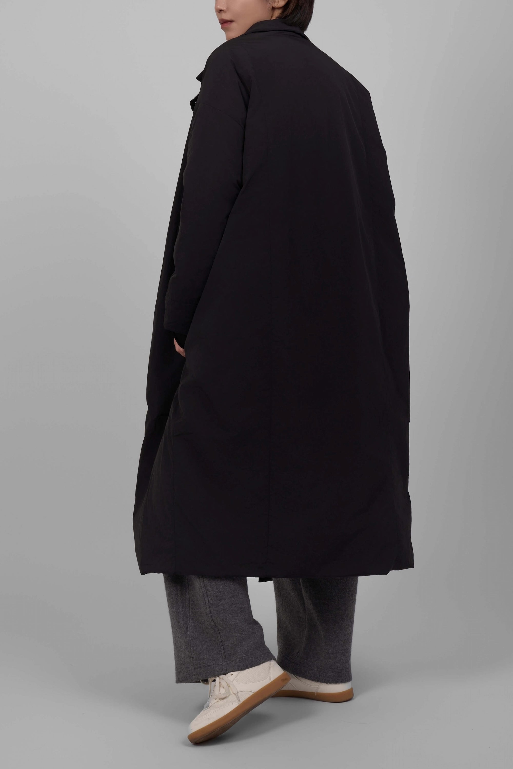 Person wearing a black coat on a gray background