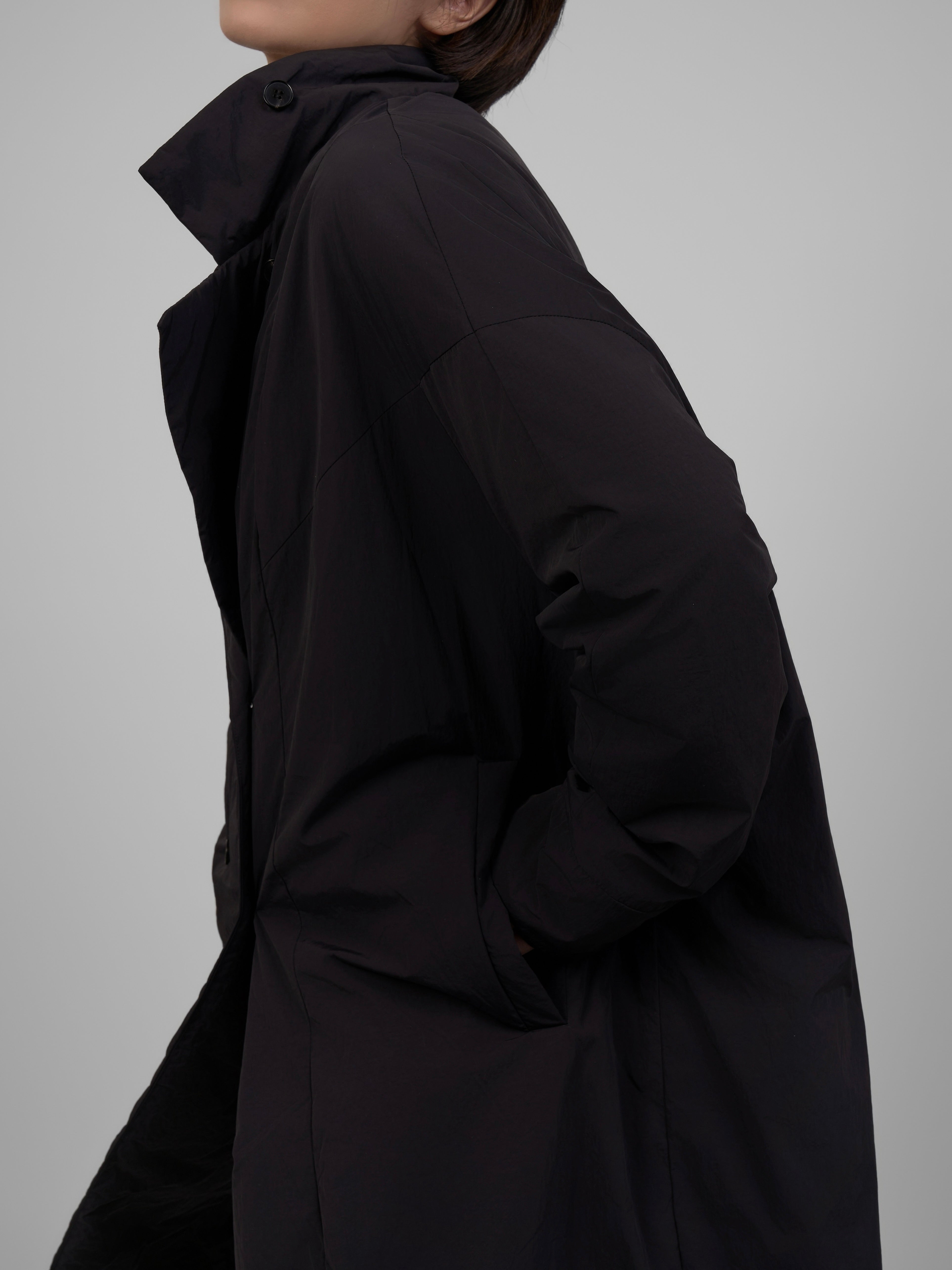 Back view close-up of black oversized down coat showing silhouette and fabric texture.