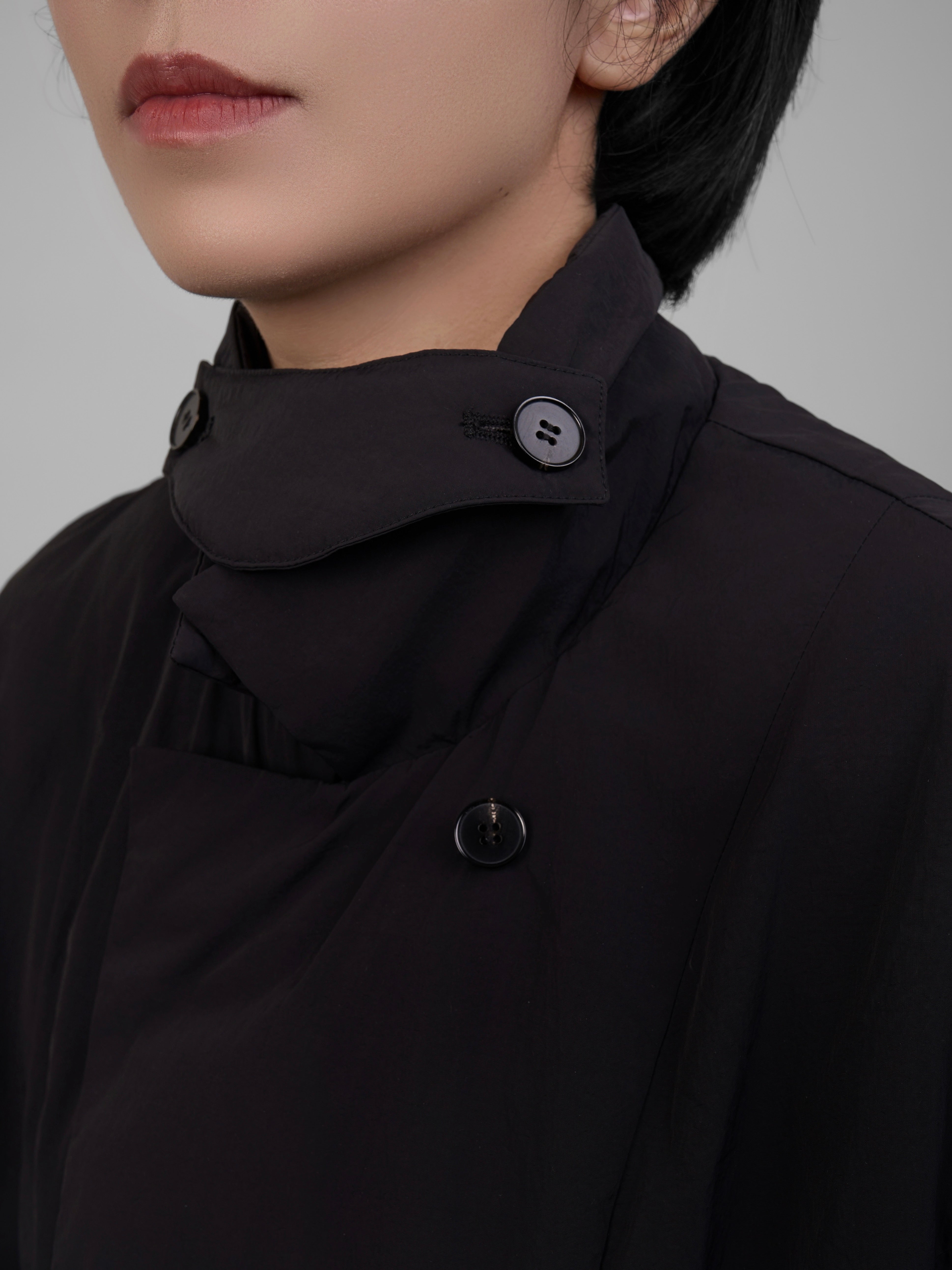 Close-up of the collar and button details on the black oversized down coat.
